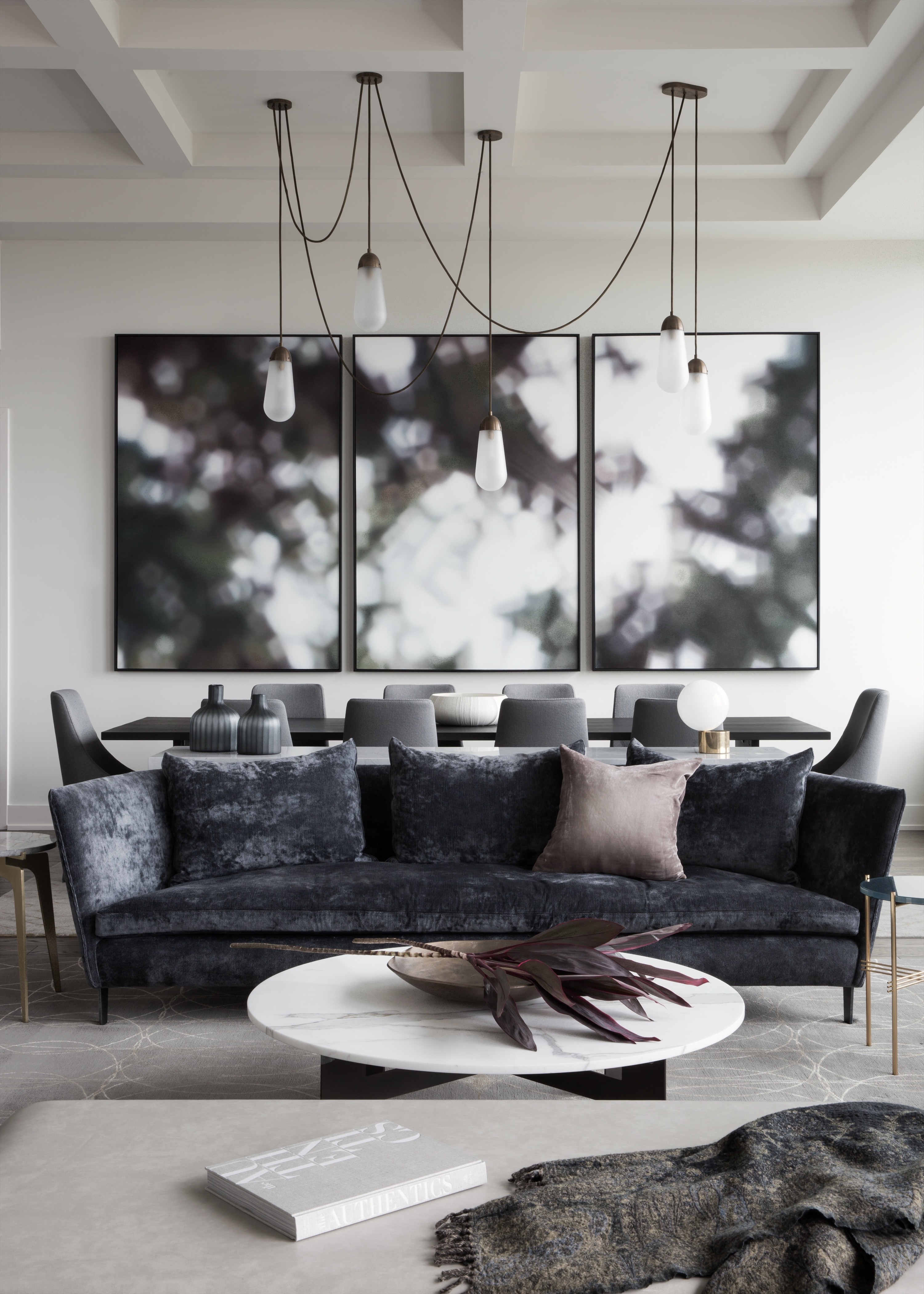 A blue velvet sofa beneath a triptych and glass pendants in a Midtown pied-à-terre