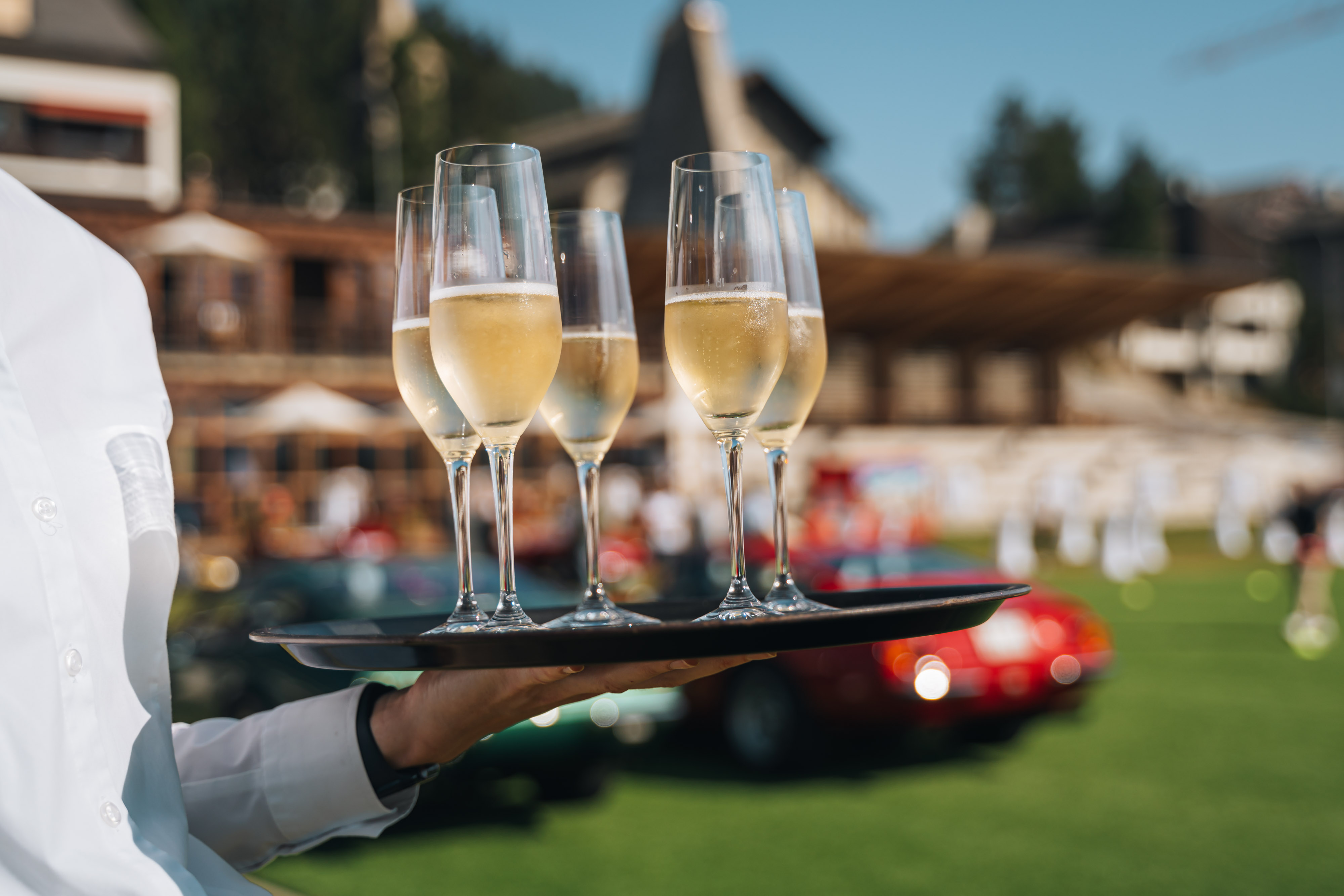 cameriere con calici di vino ad evento di auto classiche