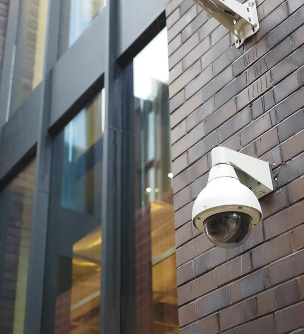 Dome security camera mounted on a brick building wall to watch over the grounds