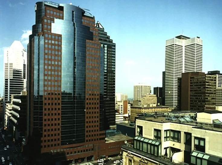City skyline with modern skyscrapers under a clear blue sky. The tallest building features reflective glass and brown accents, exuding urban sophistication.