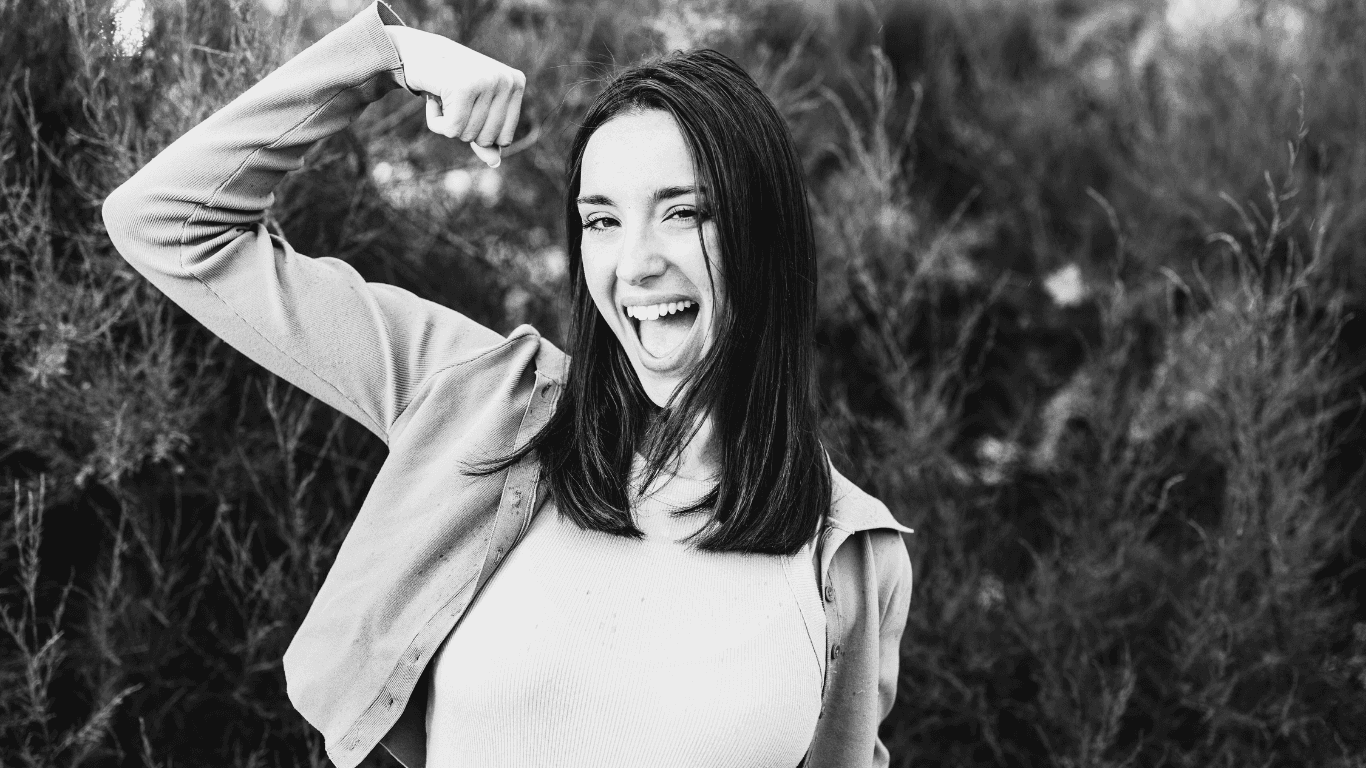Confident professional woman flexing her arm, representing empowerment, growth, and human potential in the workplace.