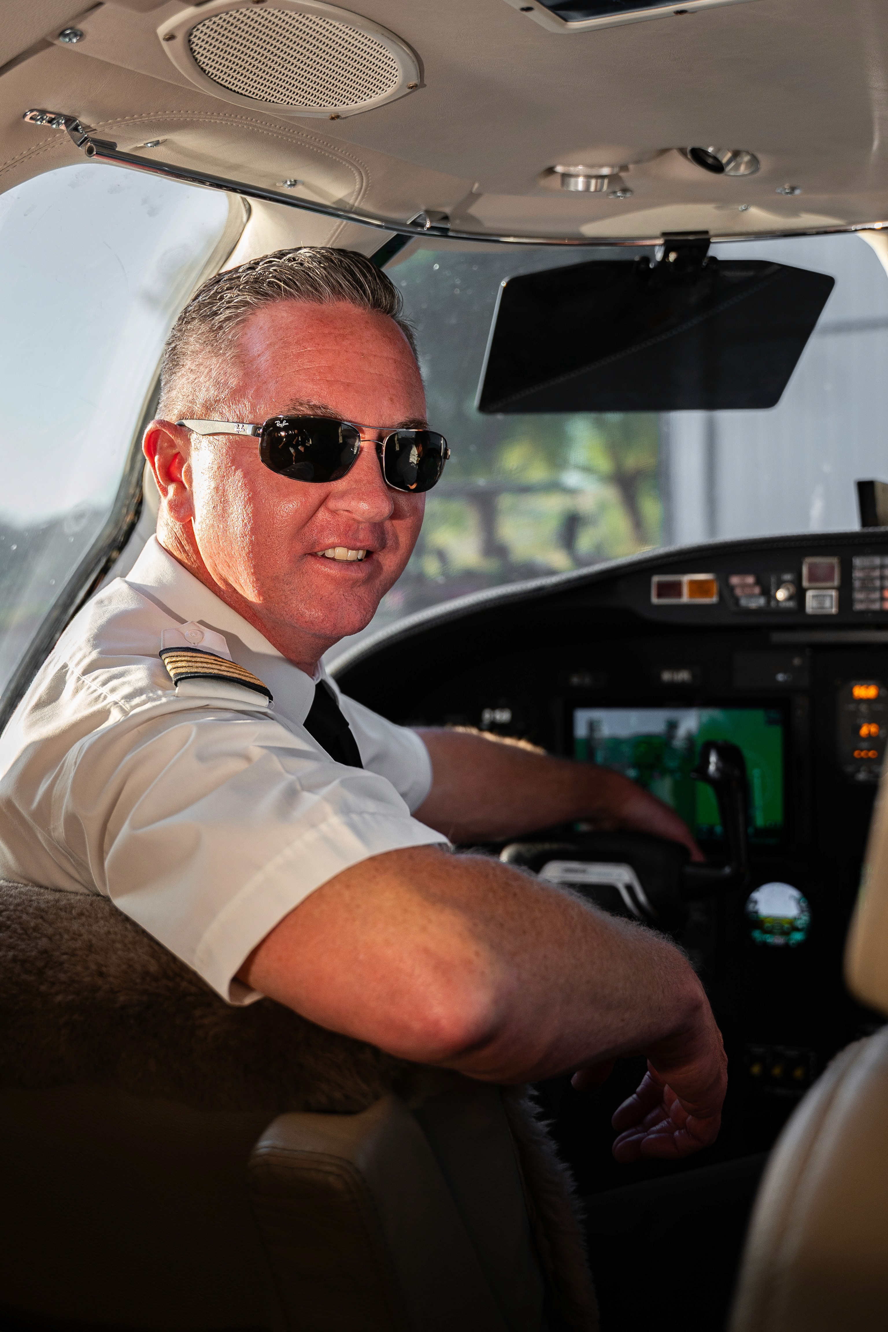 Man wearing headphones and a white t-shirt working on a laptop in soft natural light, with window shadows cast on the wall.