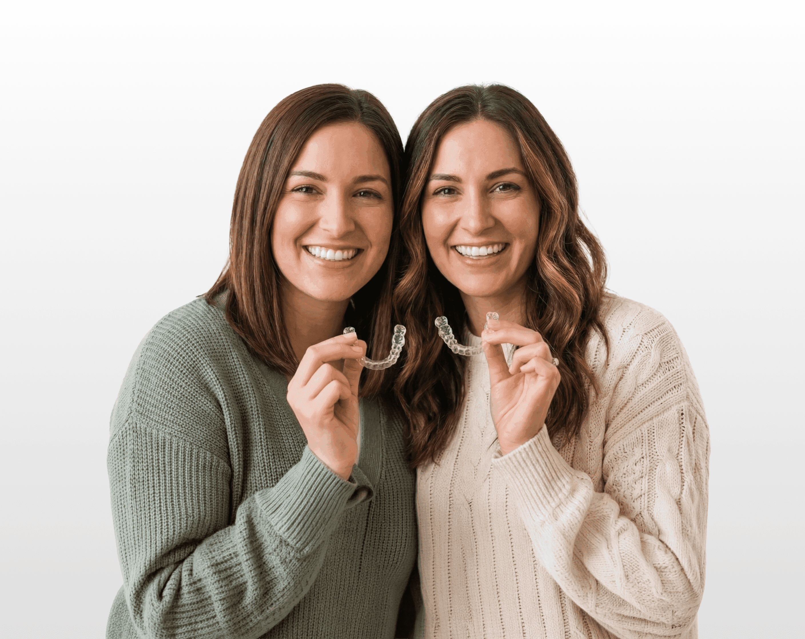 Invisalign in Dubai with a woman smiling confidently, holding her clear aligners, highlighting discreet and effective treatment.