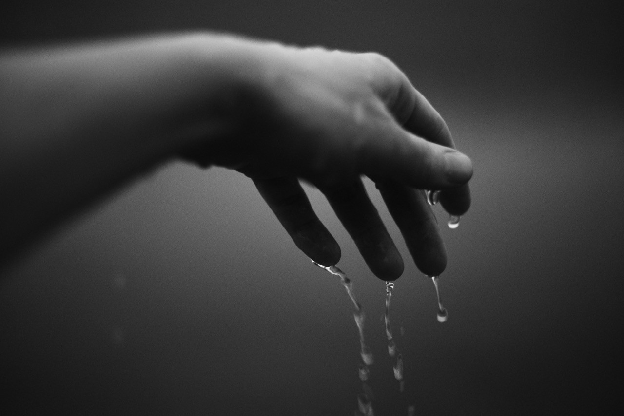 Water dripping from a hand in black and white.
