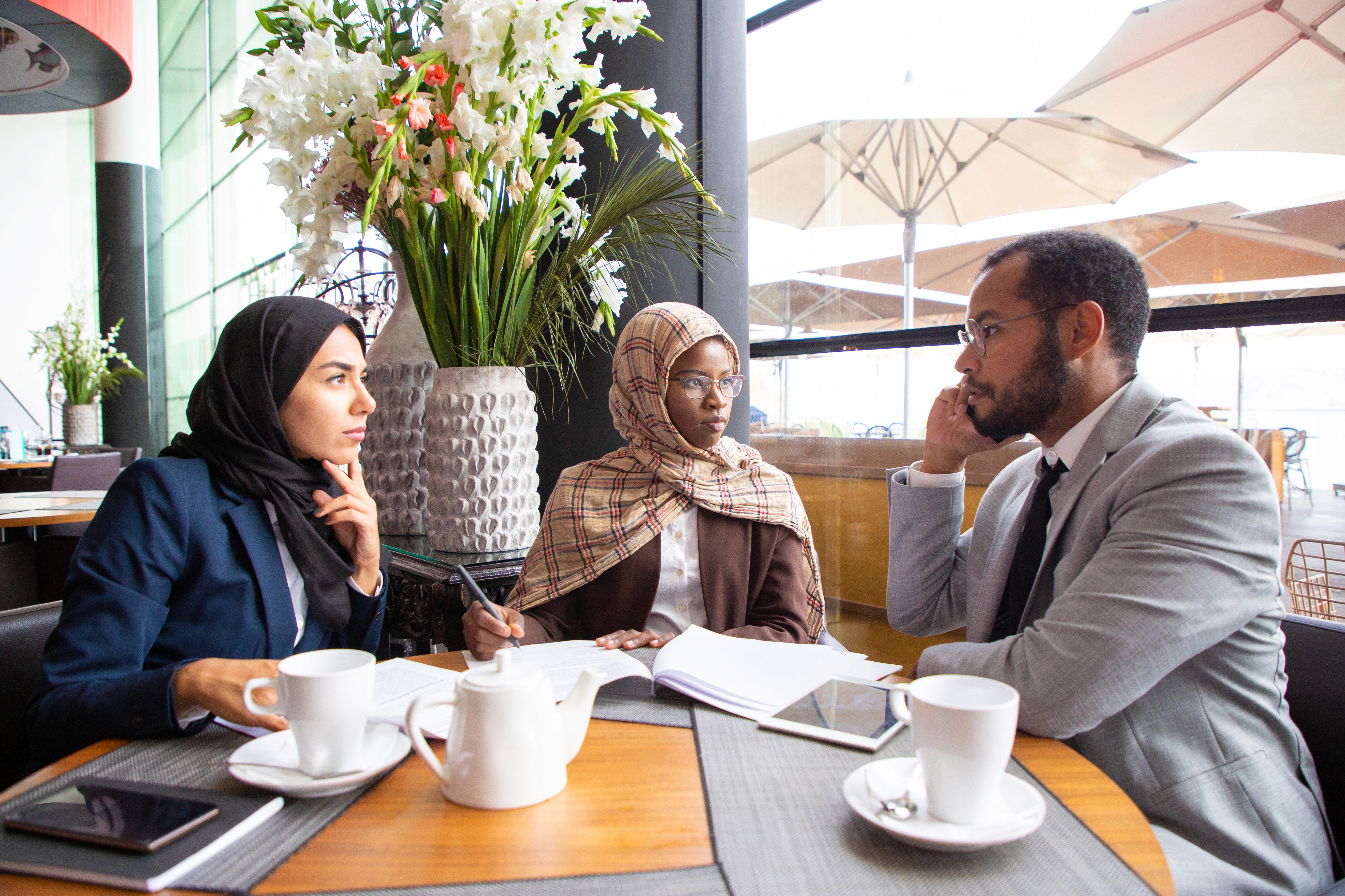 Professional consultants discussing the specific requirements for obtaining an ADGM license during a meeting at a local cafe.