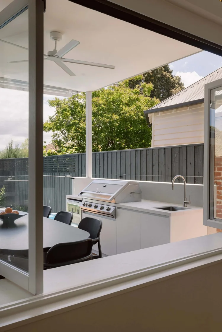 Modern outdoor kitchen with BBQ grill and dining table on patio.