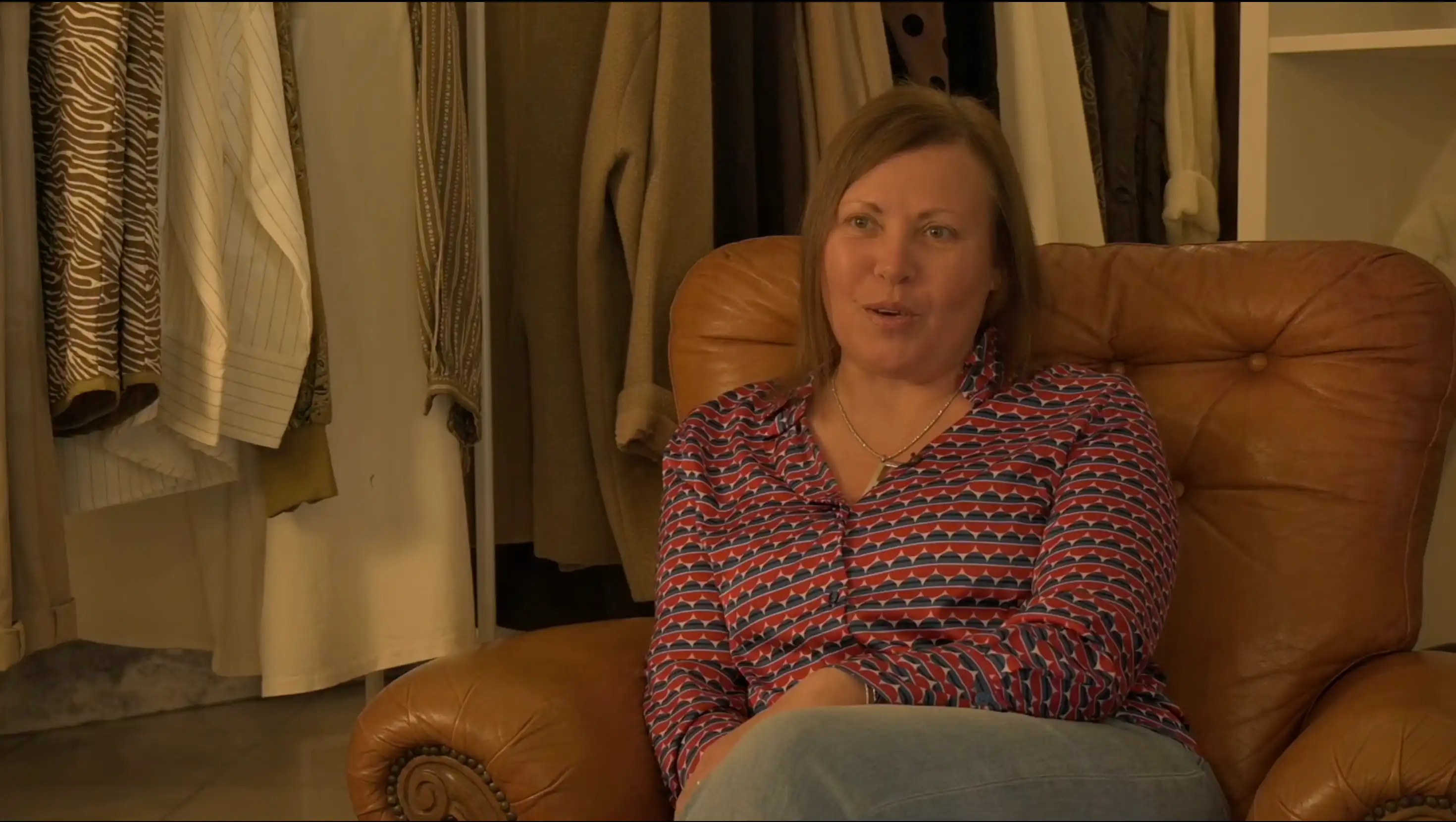 Donna seduta su una poltrona in pelle dentro un negozio di abbigliamento mentre viene intervistata per il documentario donne in bilico