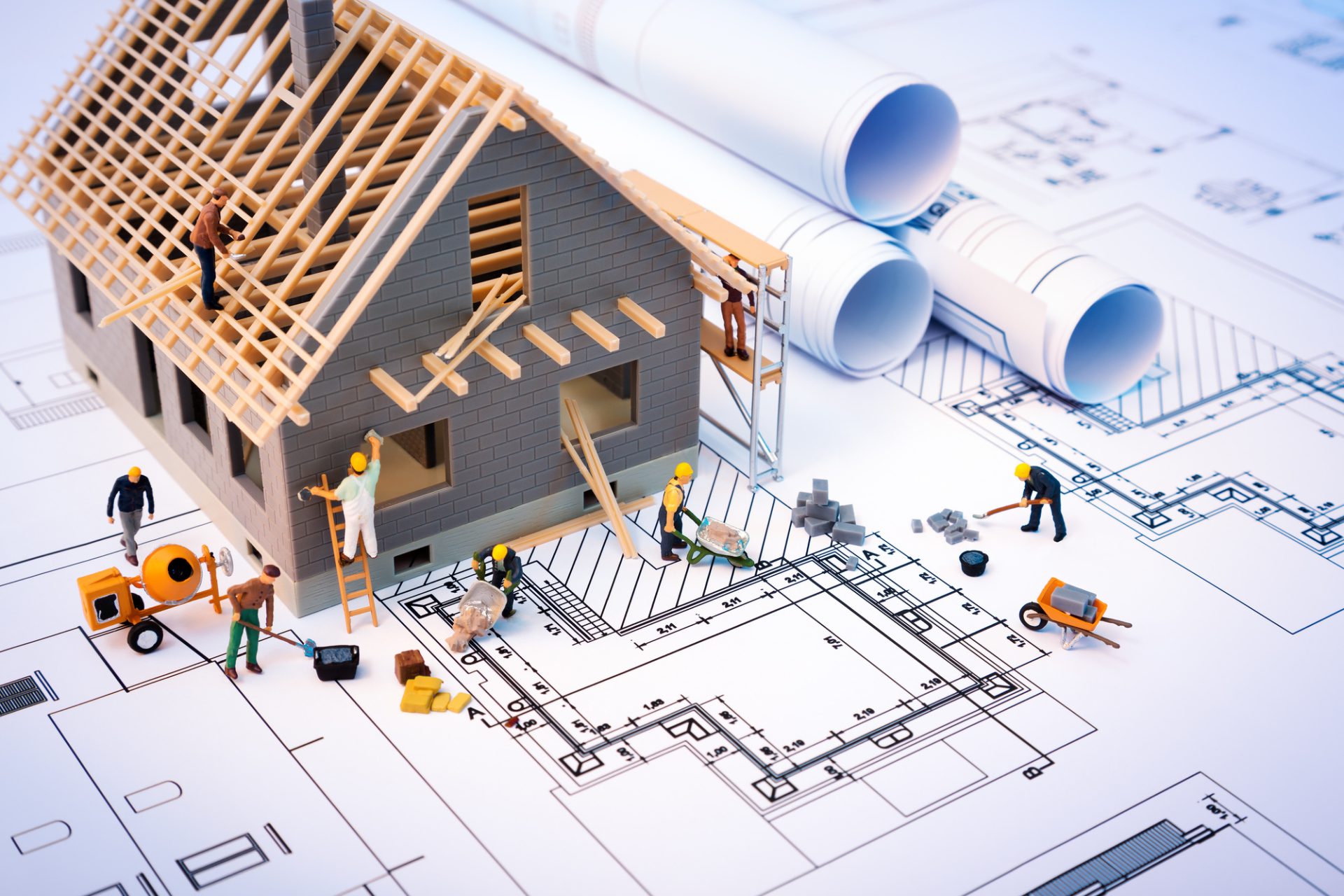 Miniature construction scene on blueprints with model house.