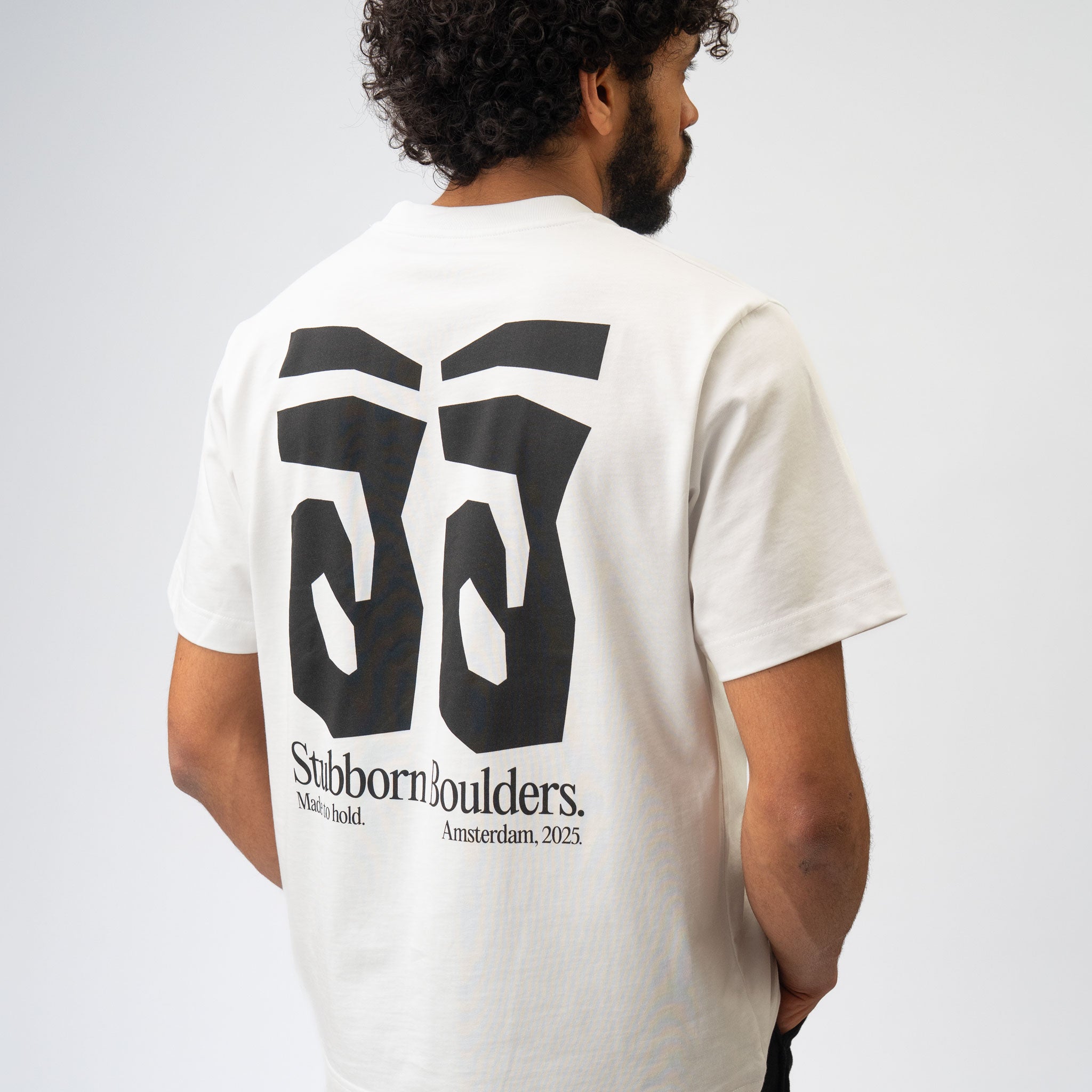 Person wearing a white t-shirt with a black logo and text on the back, on a plain background