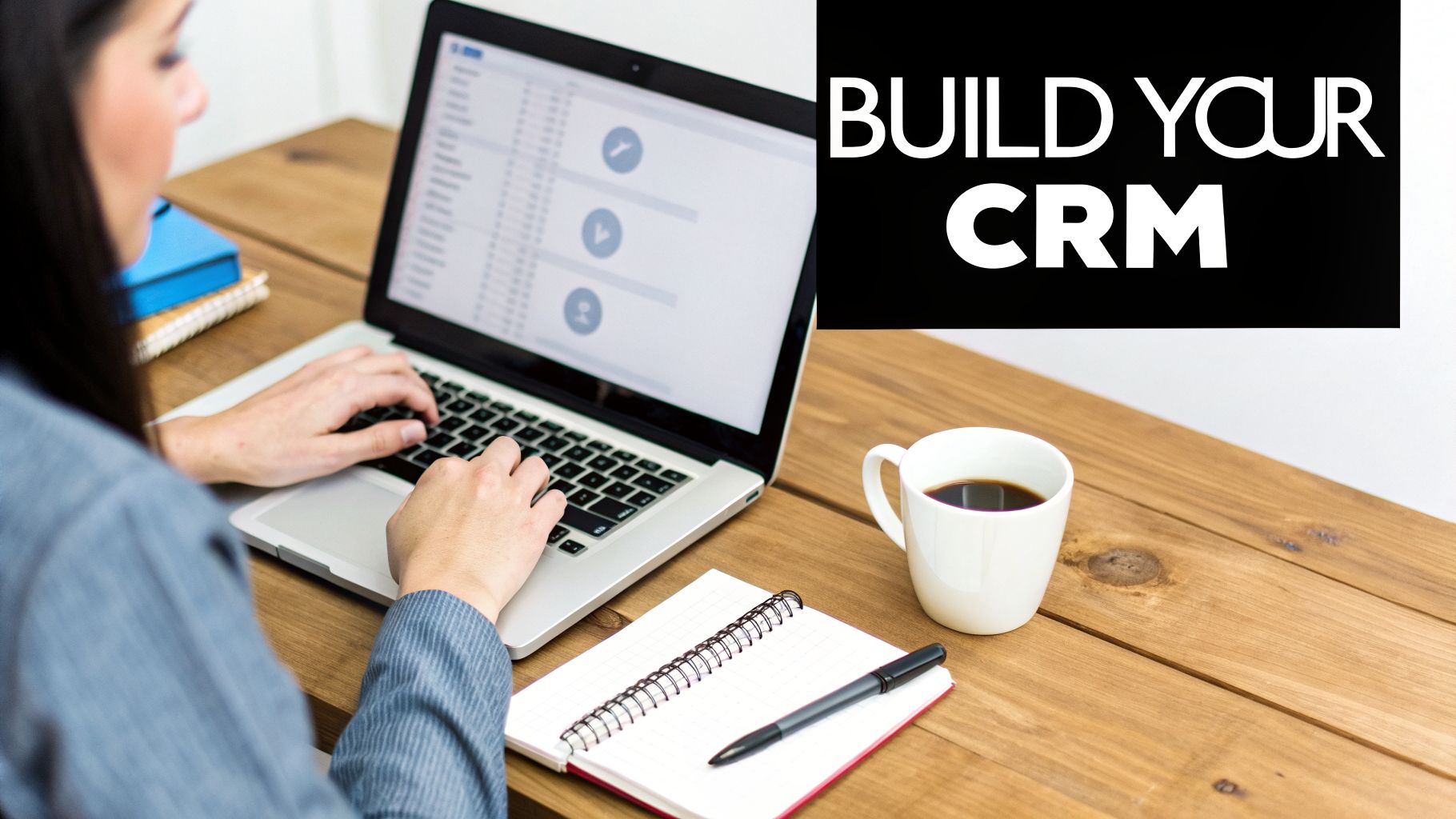 Woman working on a laptop at a wooden desk with coffee, notebook, and 'BUILD YOUR CRM' text.