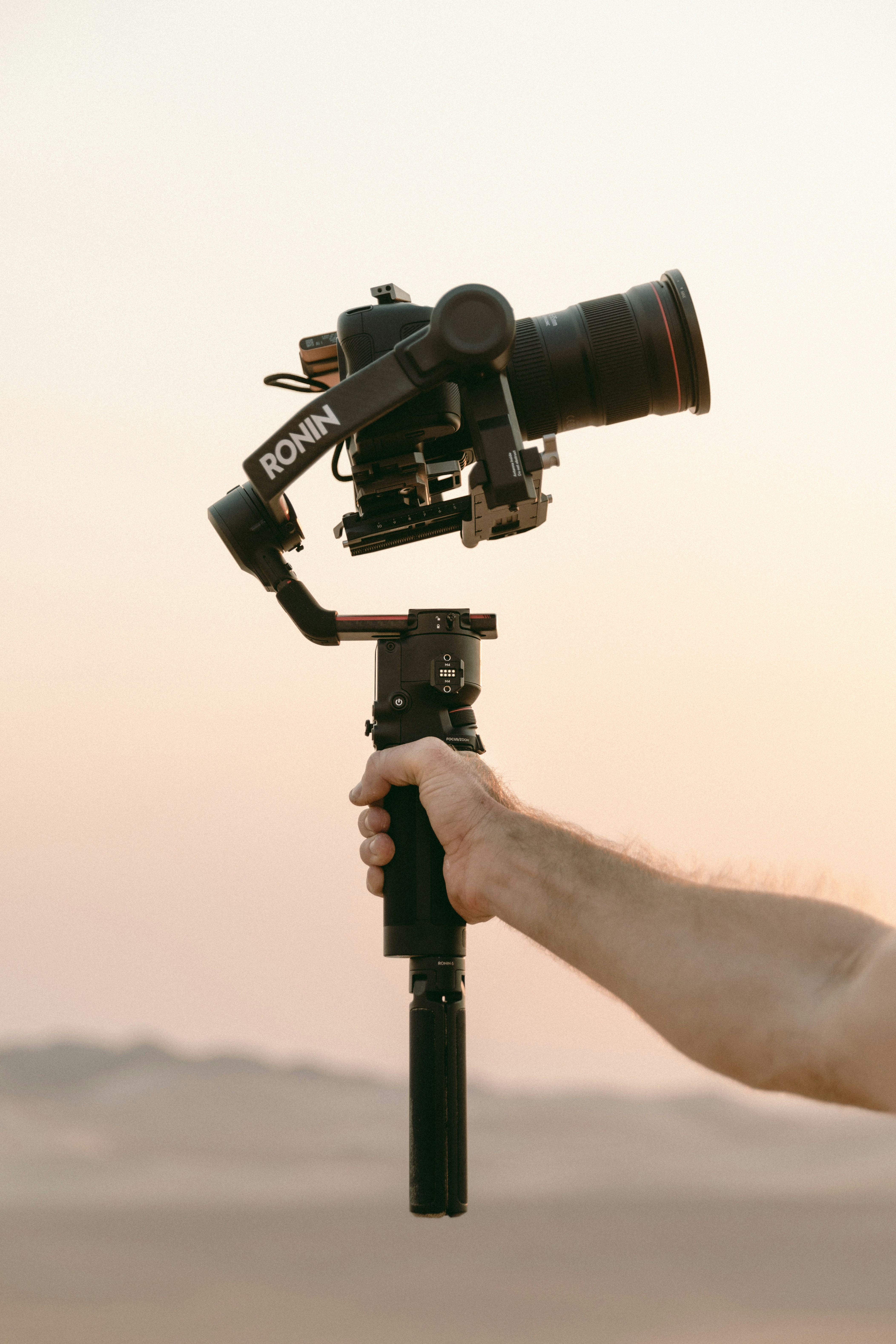 person holding black mirrorless camera on a gimbal