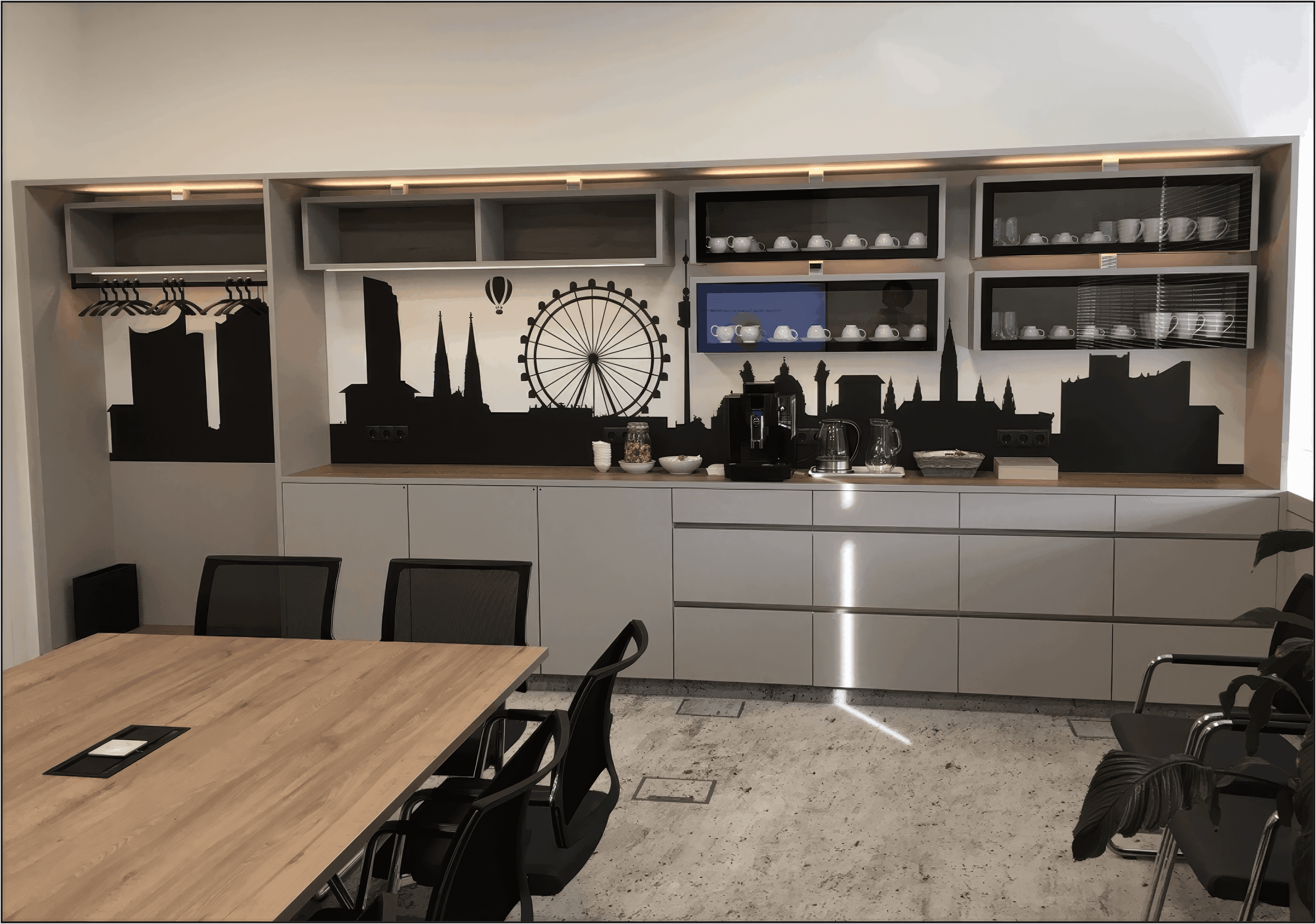 MW Interior - Moderne Kaffeebar mit Stadtsilhouetten-Wandmotiv, Einbaukaffeeautomat und beleuchteten Regalen im Büro" Beschreibung: Stilvolle Catering-Einheit mit dekorativem Stadtpanorama-Motiv, beleuchteten Einbauregalen für Tassen, integriertem Kaffeevollautomaten und griffbereitem Geschirr – Wohlfühlambiente im Büroalltag.Moderne Kaffeebar mit Stadtsilhouetten-Wandmotiv, Einbaukaffeeautomat und beleuchteten Regalen im Büro" Beschreibung: Stilvolle Catering-Einheit mit dekorativem Stadtpanorama-Motiv, beleuchteten Einbauregalen für Tassen, integriertem Kaffeevollautomaten und griffbereitem Geschirr – Wohlfühlambiente im Büroalltag.