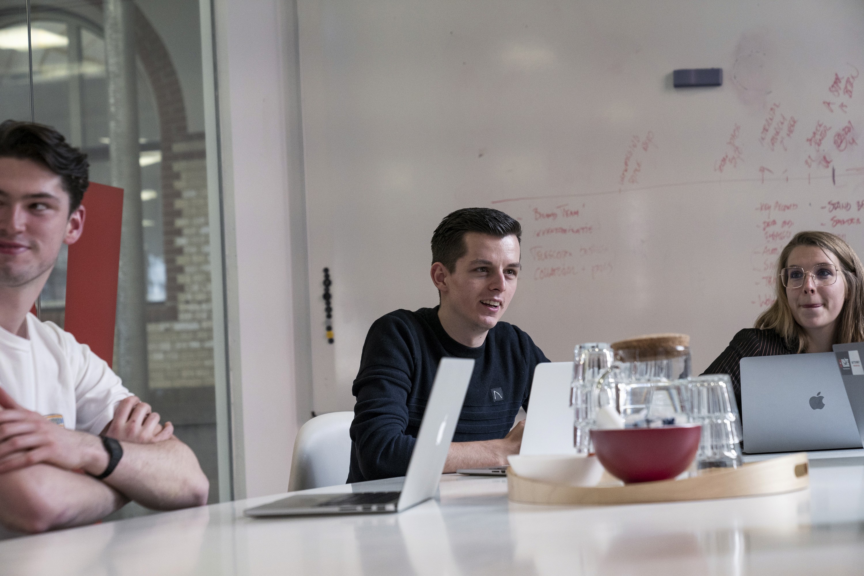 a group of people in a meeting with a whiteboard in the background