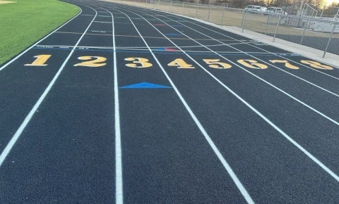 Black running track with lane numbers and markings after warranty and maintenance planning.