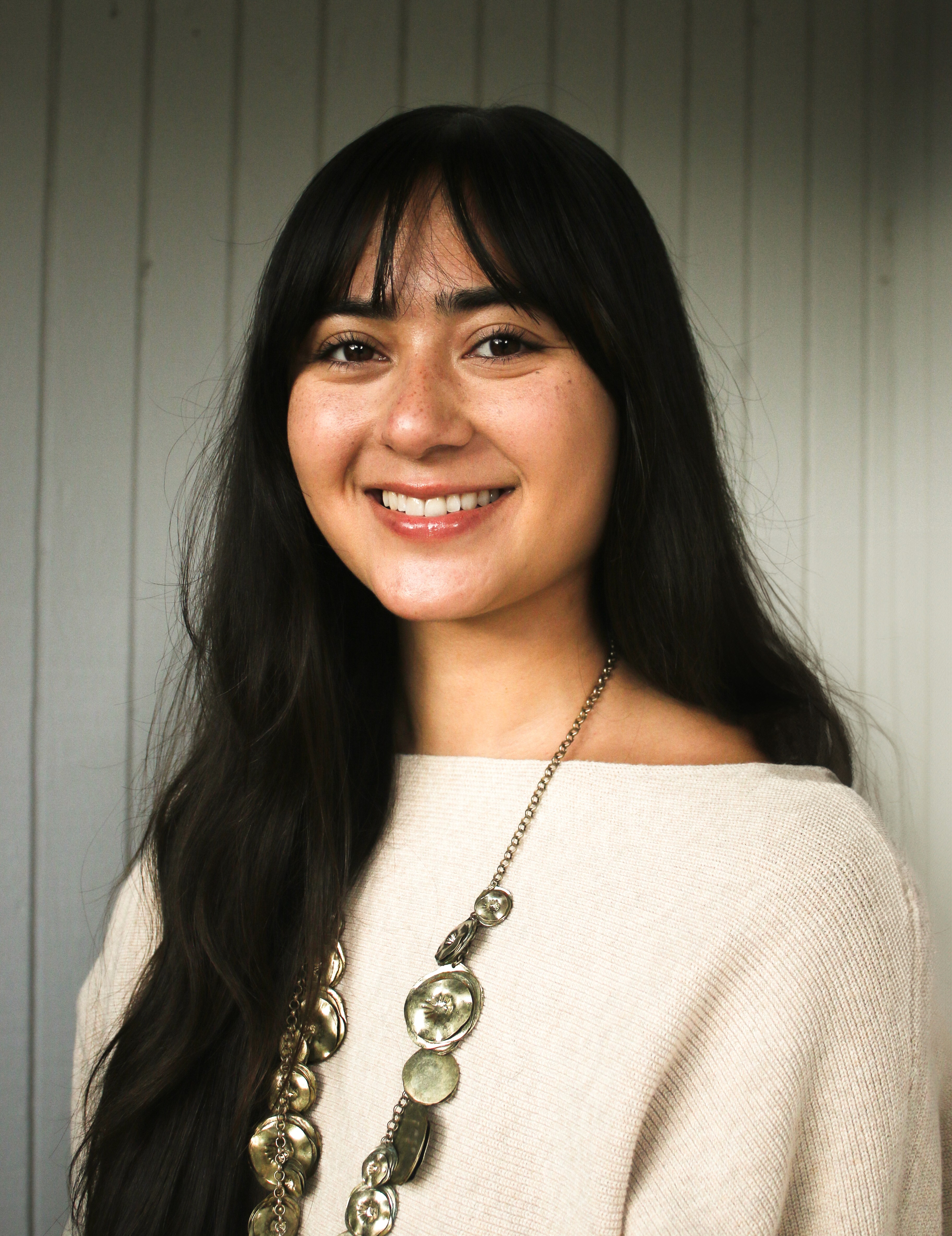 A thoughtful young person with dark hair gazes to the side, captured in soft black and white lighting.