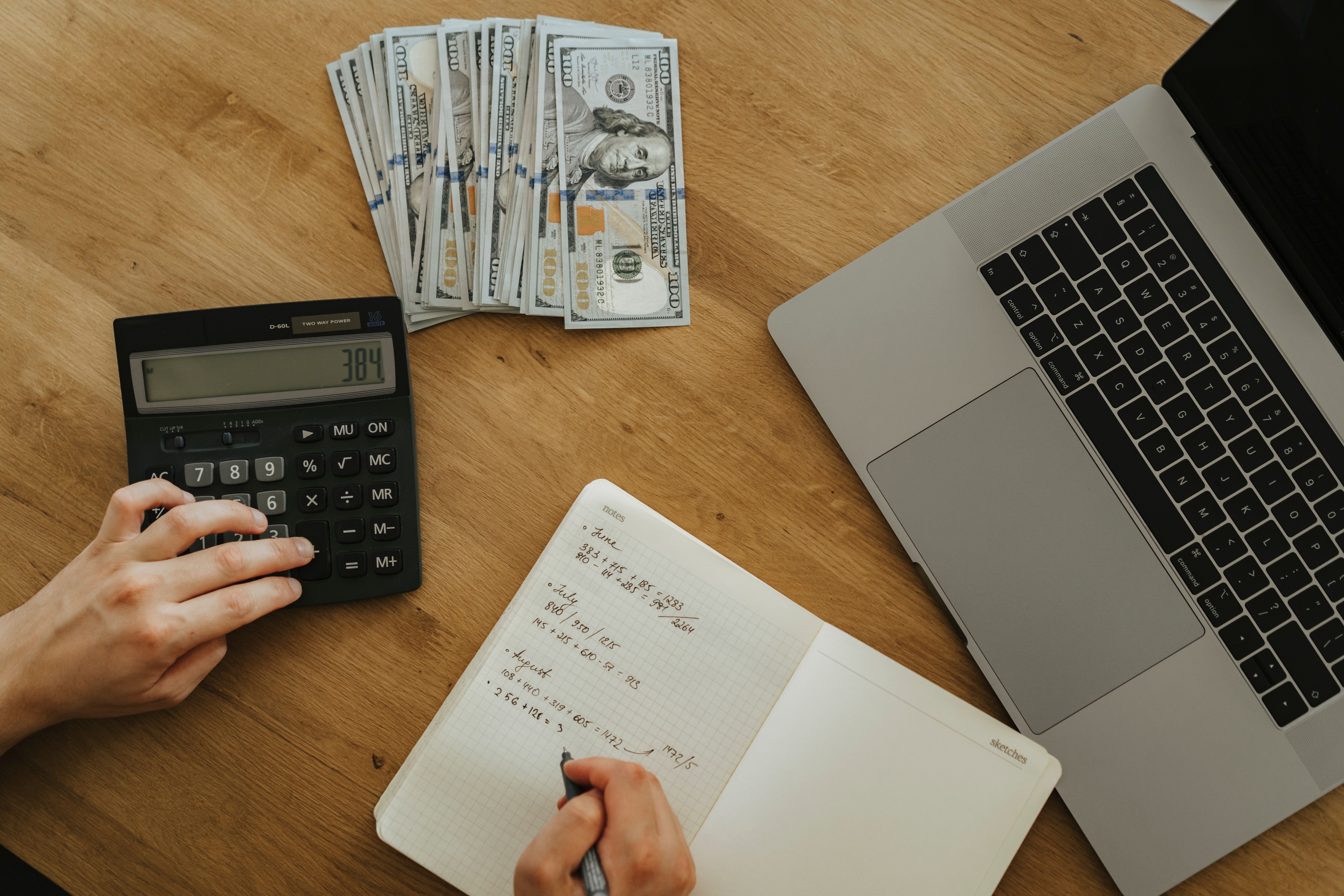 Calculator, notes and a laptop for working out a website budget