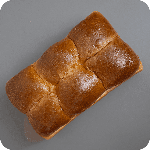 Vista desde arriba del pan brioche dulce, con greñado suave y brillo característico.