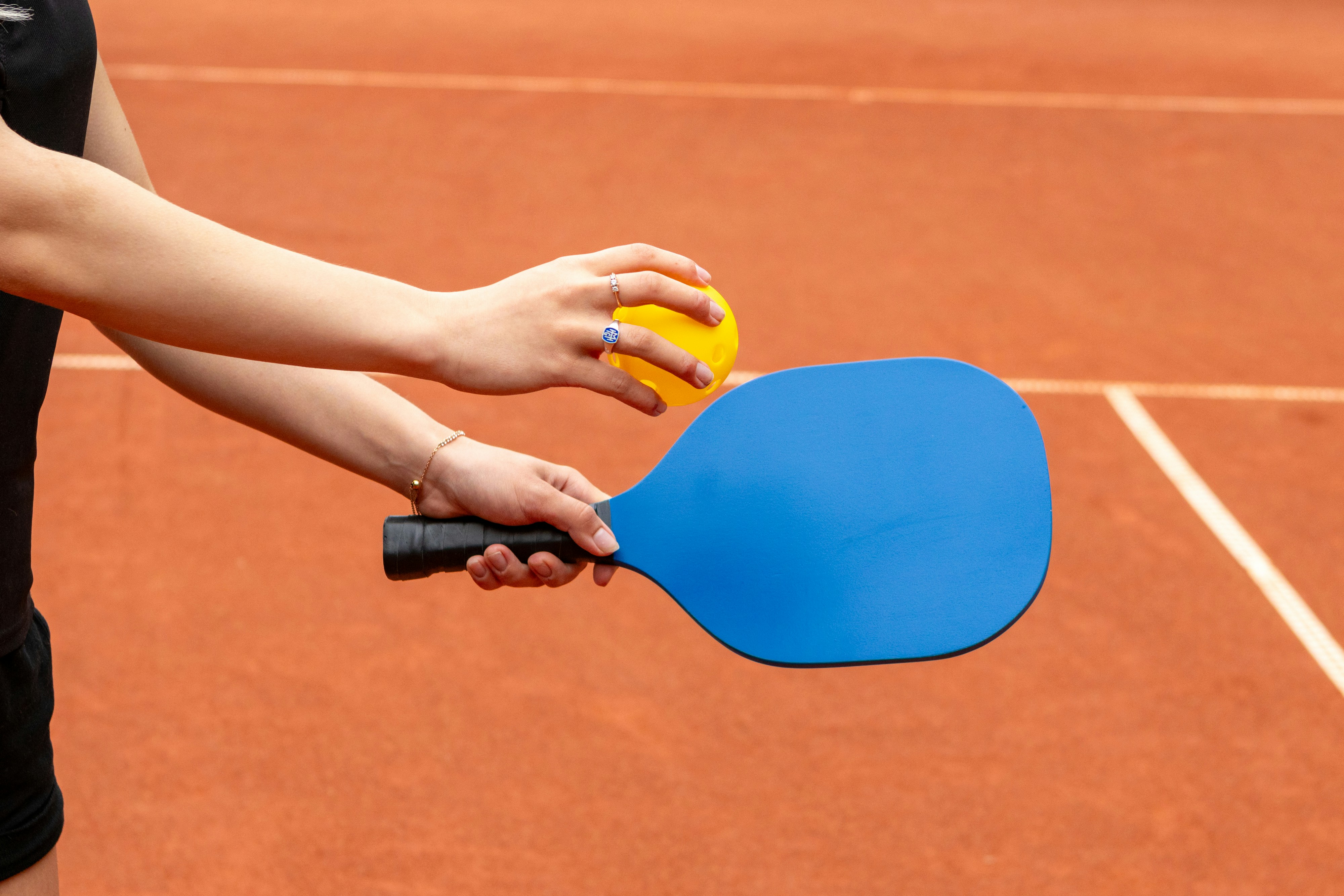 a person holding a ping pong paddle on a tennis court