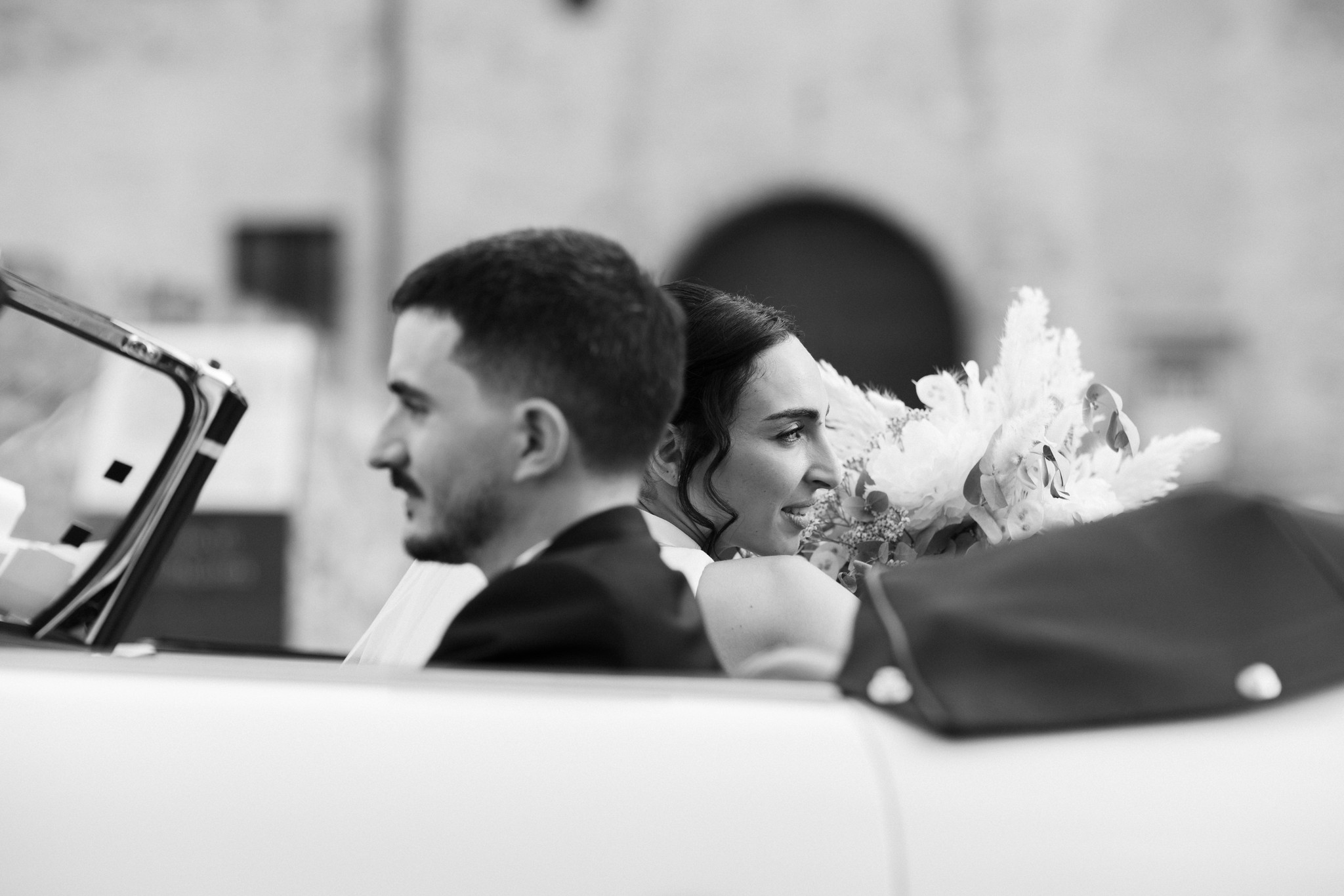 Sposi in auto dopo la cerimonia al Parco di Montebello, la sposa con bouquet bianco, reportage di matrimonio in bianco e nero