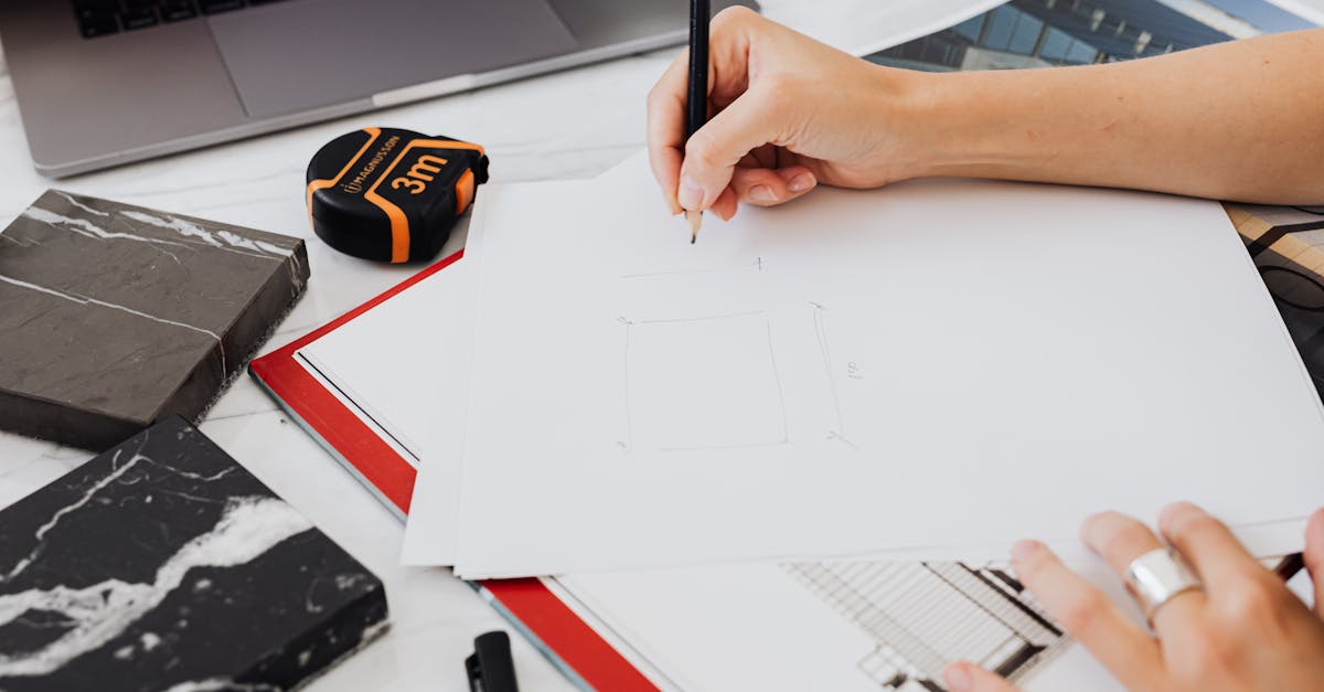 Architect drafting designs with measuring tape and materials on desk.