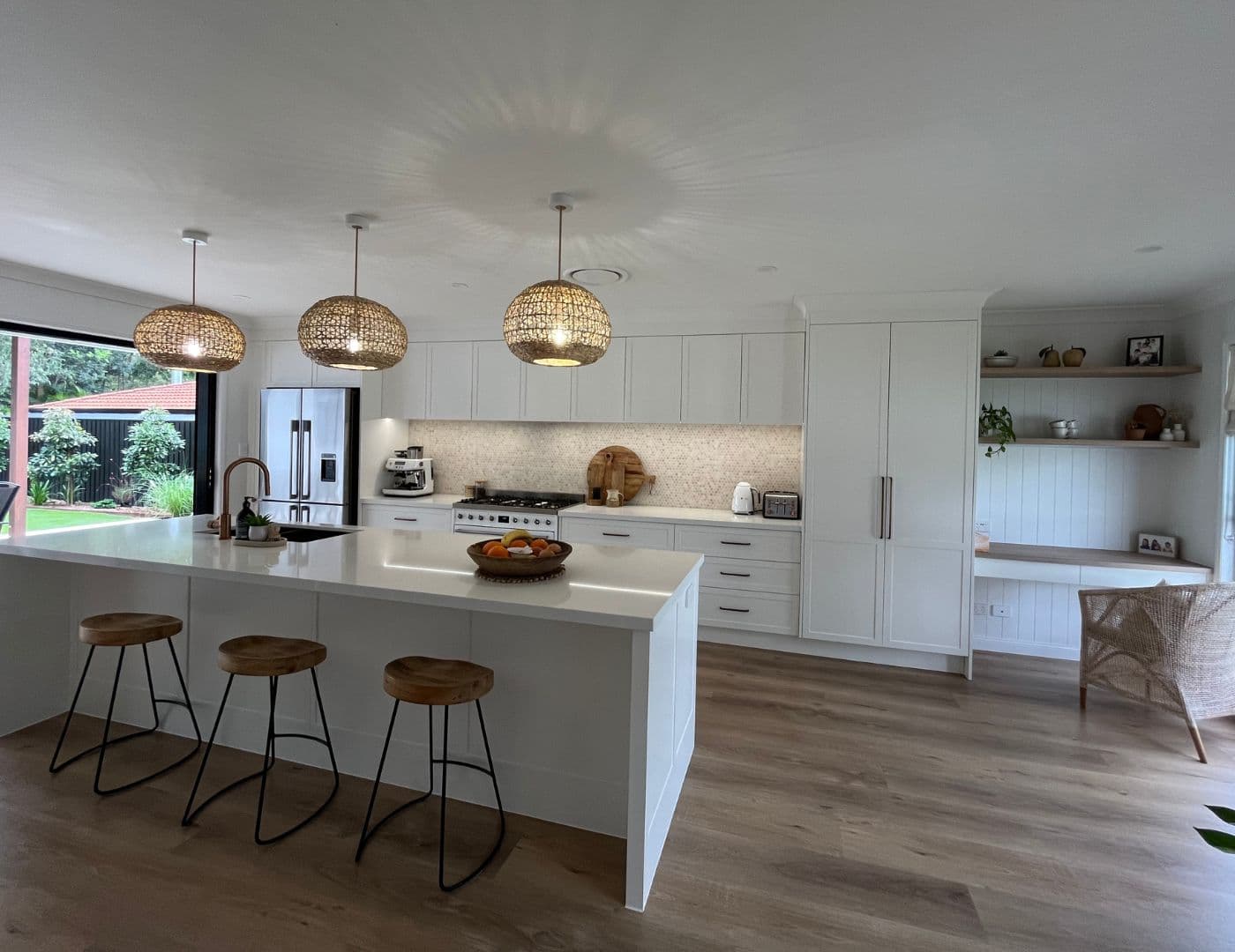 Modern kitchen renovation with white cabinets, island bench, and pendant lights in a Brisbane home.