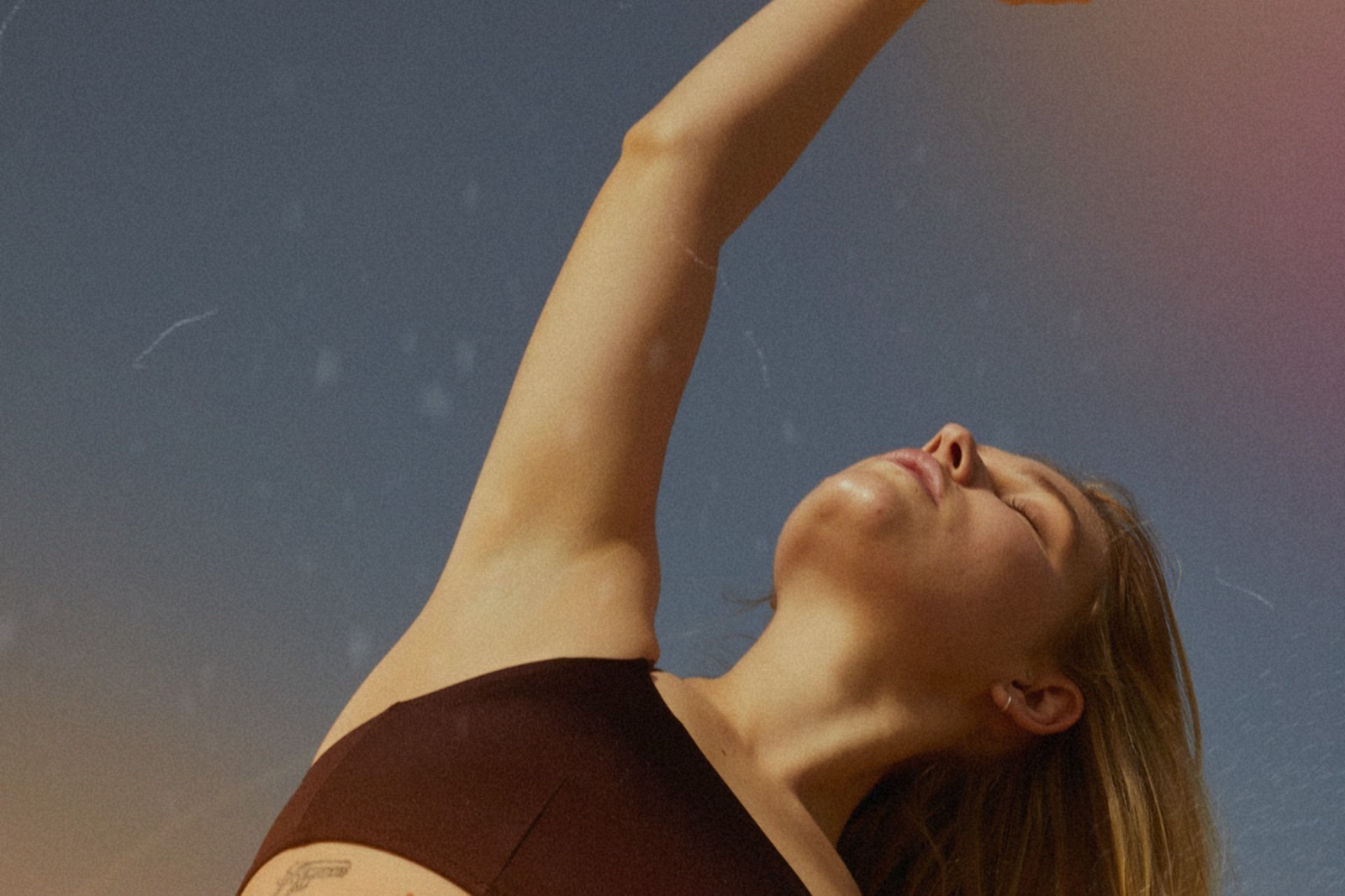 Woman in soft light stretching one arm overhead.