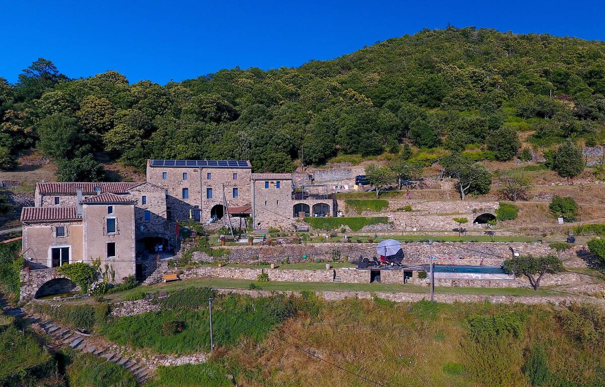 Young woman with short, dark hair and a yellow sweater looks serious, surrounded by hands holding smartphones, conveying intrusion and tension.