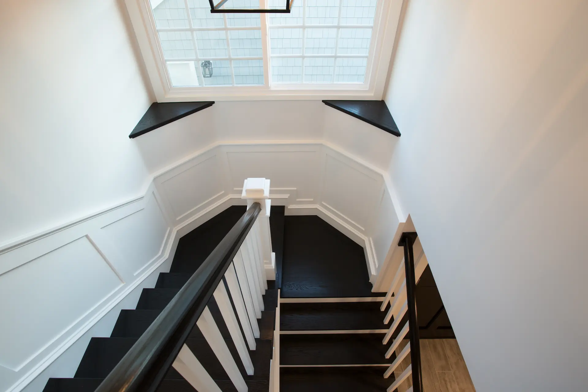 Overhead view of elegant black and white staircase, From Dana Point Cape Cod remodel, photo by Chris Darnall.