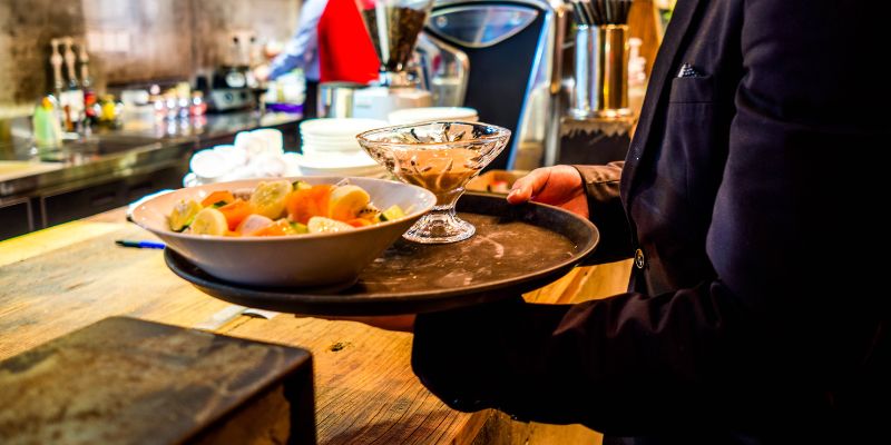 A waiter getting ready to serve food to customers in a restaurant