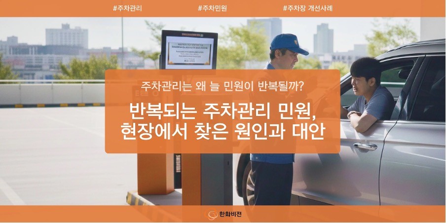 야외 주차장 차단기 앞에서 푸른색 유니폼을 입은 주차 관리원과 차량 운전자가 대화를 나누고 있는 썸네일 이미지