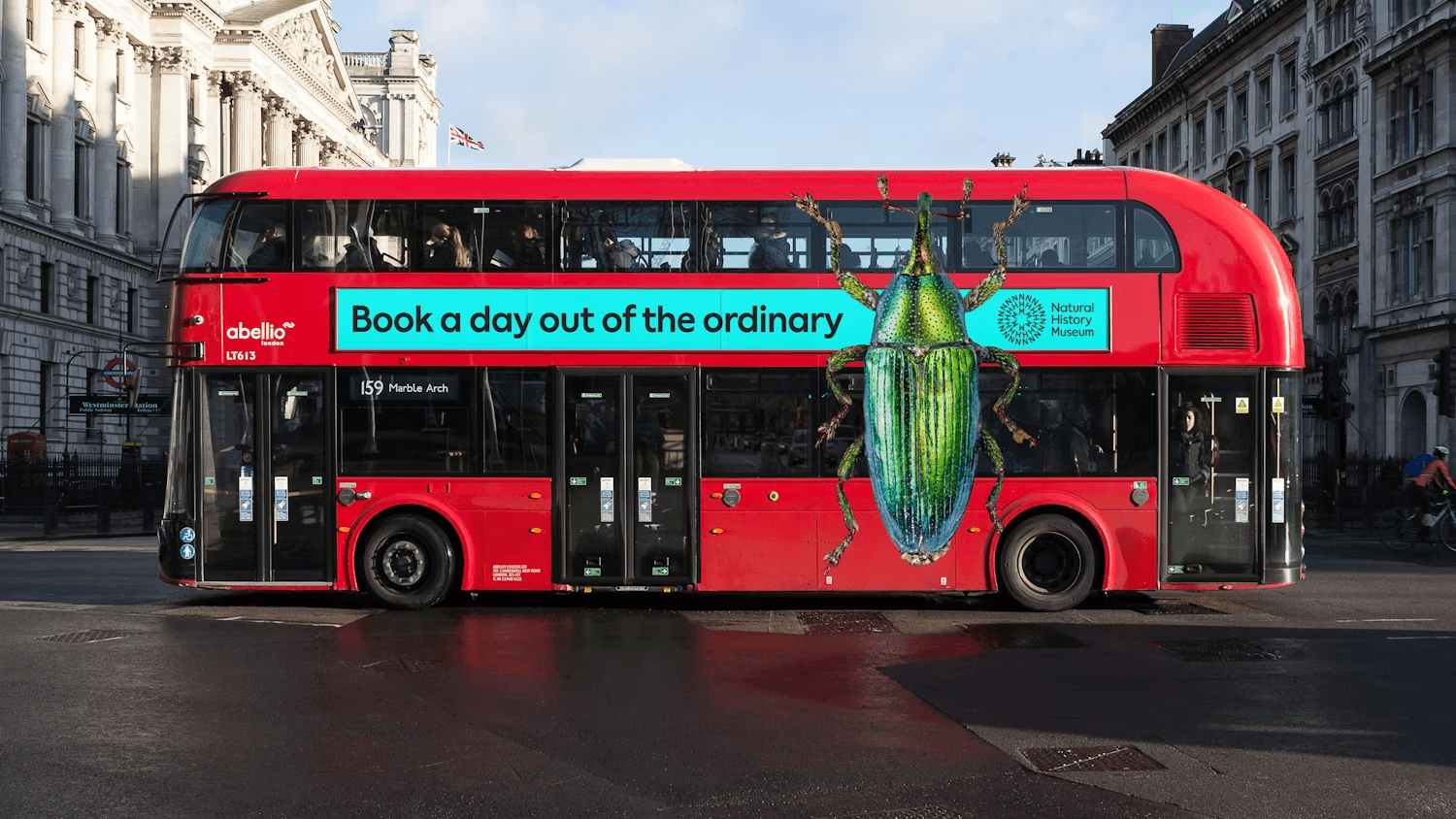 London double-decker bus featuring a Natural History Museum advertising campaign with bold typography and an oversized insect graphic.