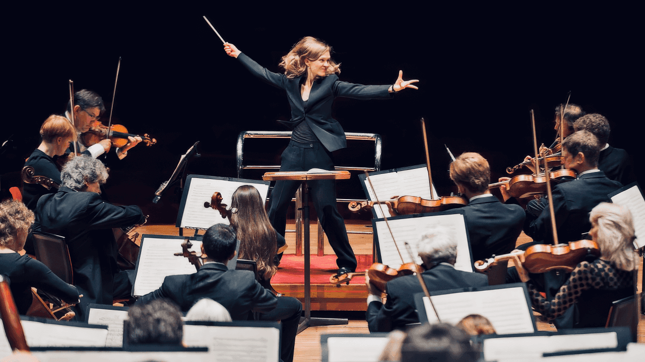 An orchestra conductor leading musicians in harmony—symbolizing the role of a super-facilitator.