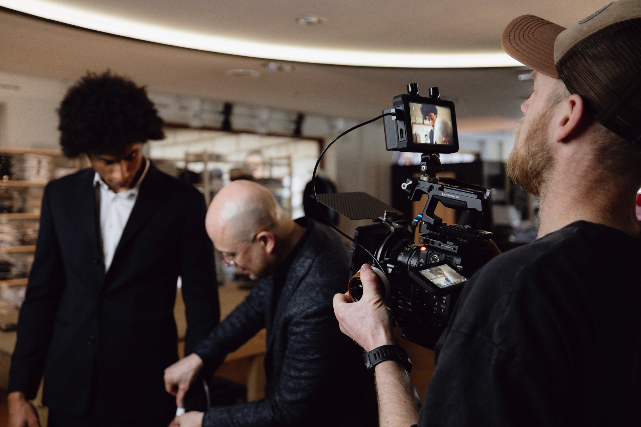 Silhouette of a camera operator filming on a professional set, surrounded by bright studio lights. The scene conveys focus and creative energy.