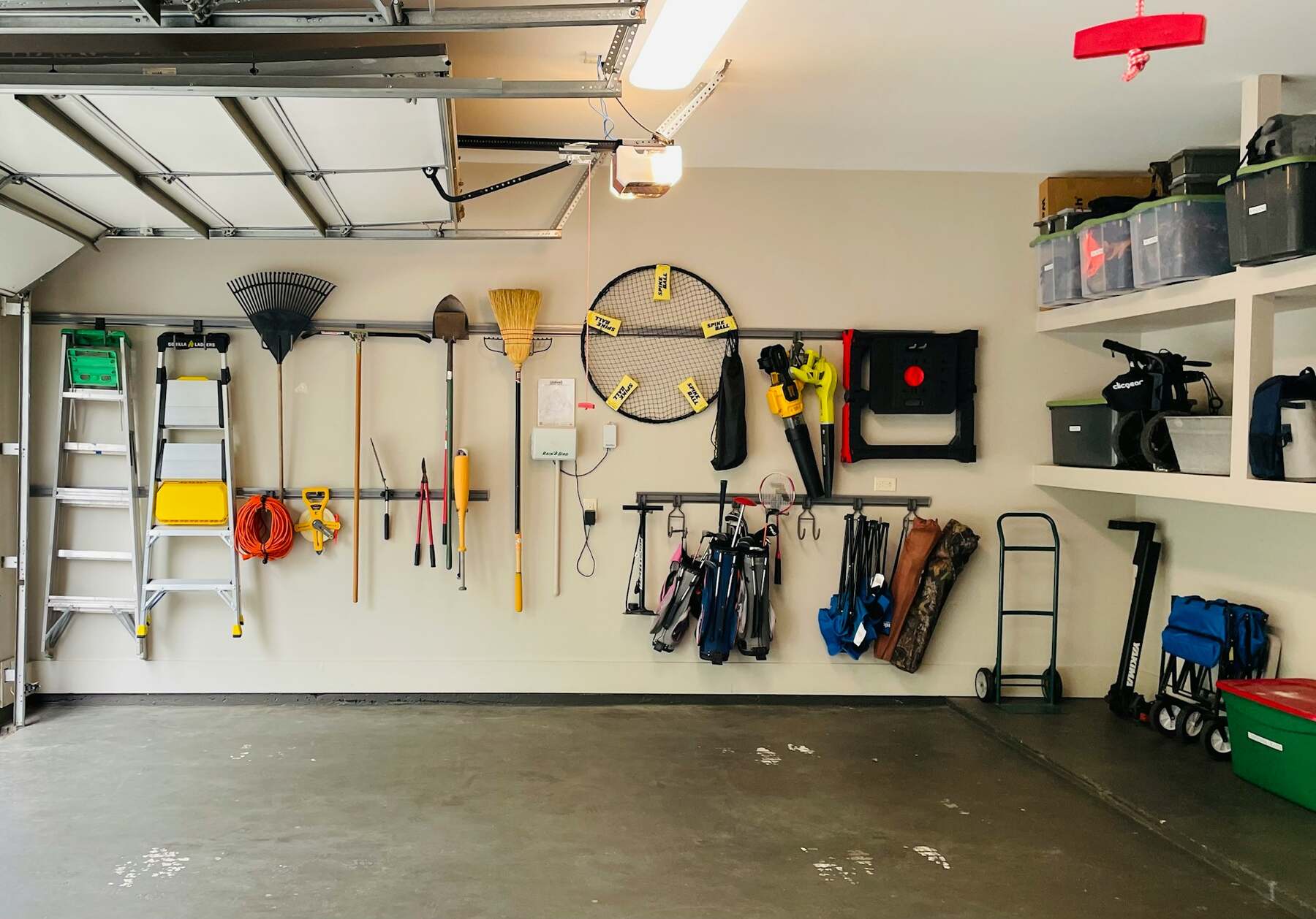 Organized garage wall with hanging tools, ladder, and storage shelves