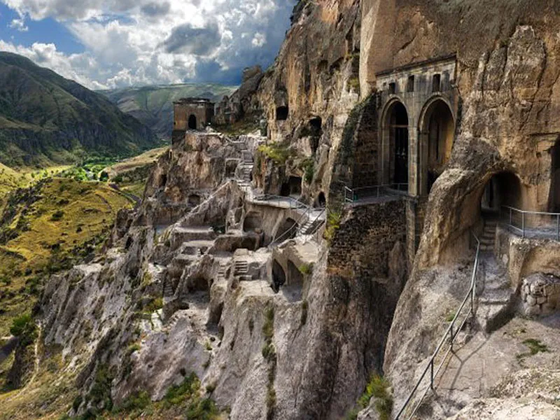 Ancient cave monastery built into a mountainside.  Multiple levels of cave dwellings and structures are visible.