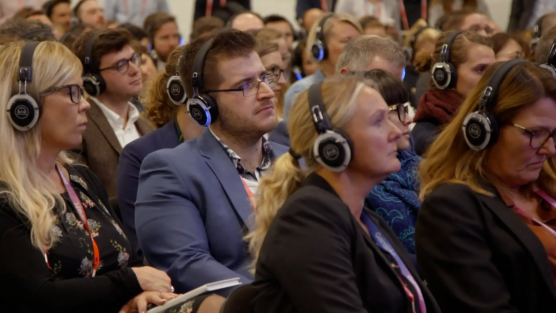 Audience members wearing headphones while listening to a live conference session.
