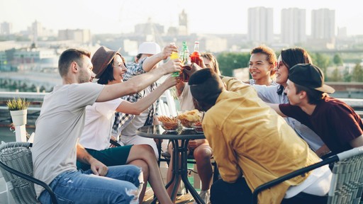 Friends toasting drinks on a rooftop party.