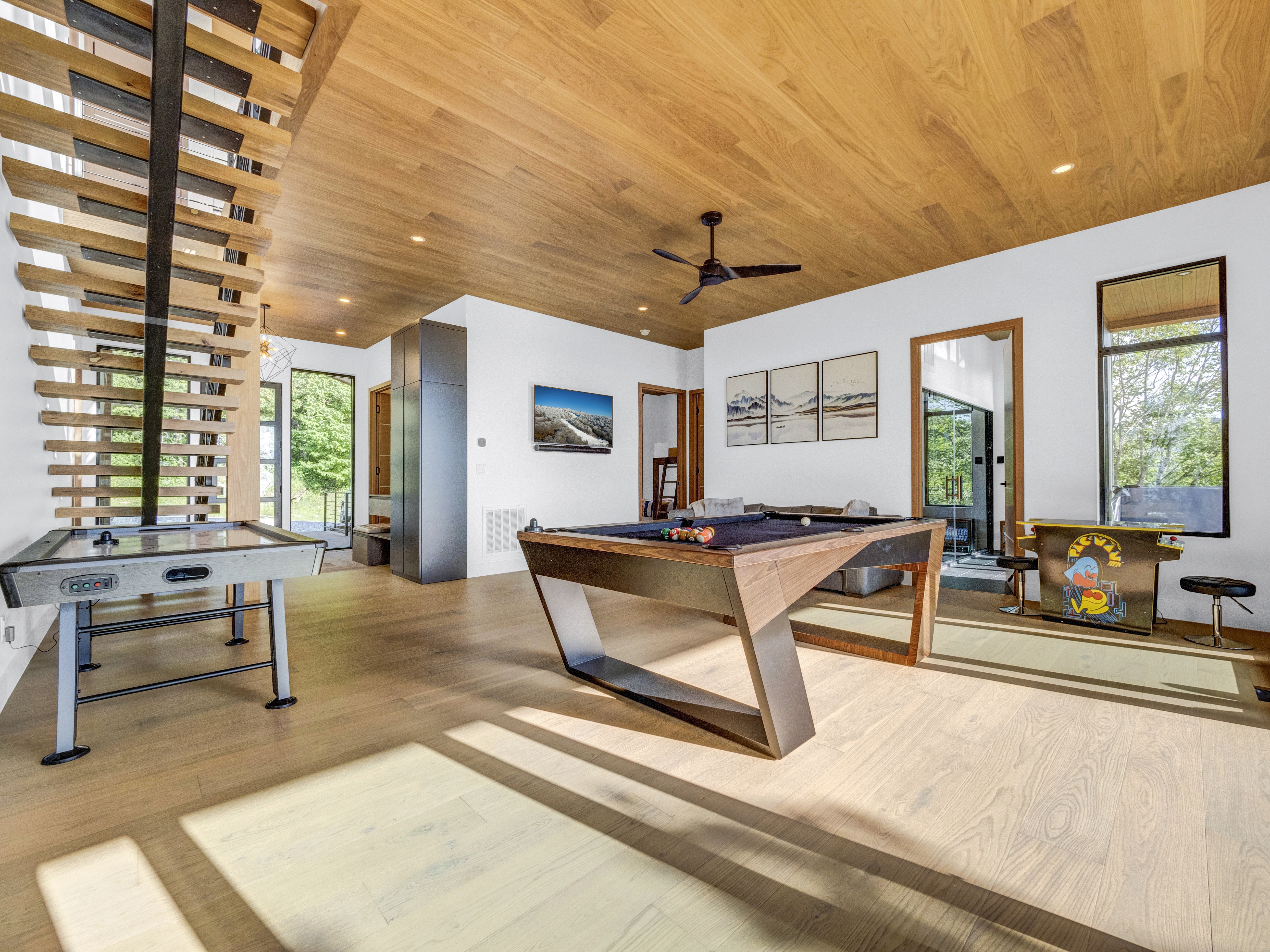 A charming hand-carved wooden bear holding a "Welcome" sign on the front porch of a modern luxury cabin