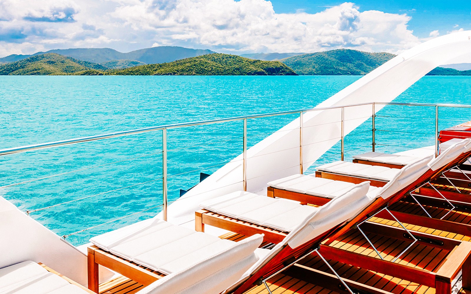 כיסאות נוח על סיפון סירה המשקיפים על מים טורקיז ואיים במהלך סיור היום 'זיגזג וויטסאנדייז'.