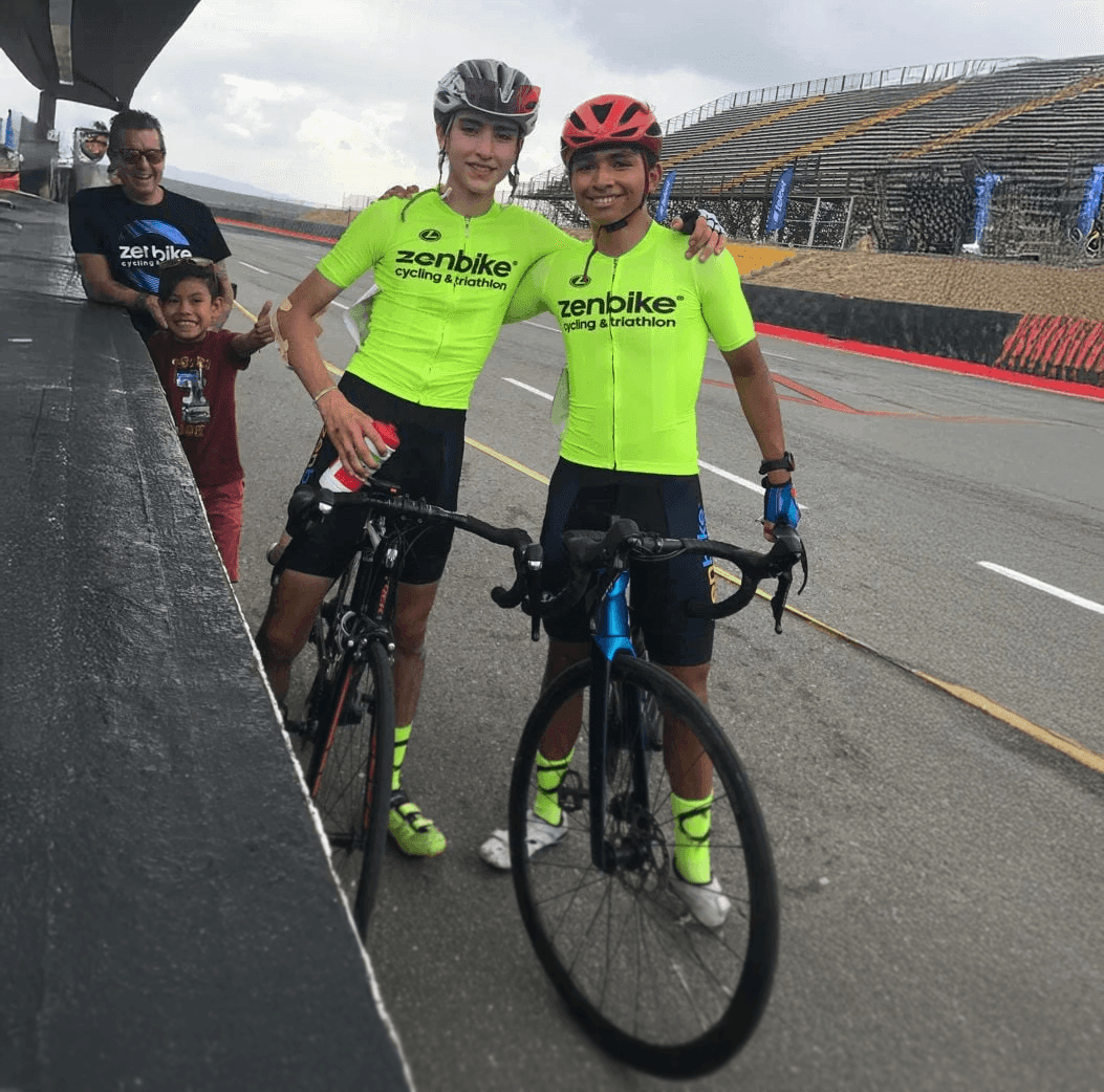 Ciclistas juveniles ZenBike en uniforme neón posan sonrientes tras competir en el Autódromo Hermanos Rodríguez.