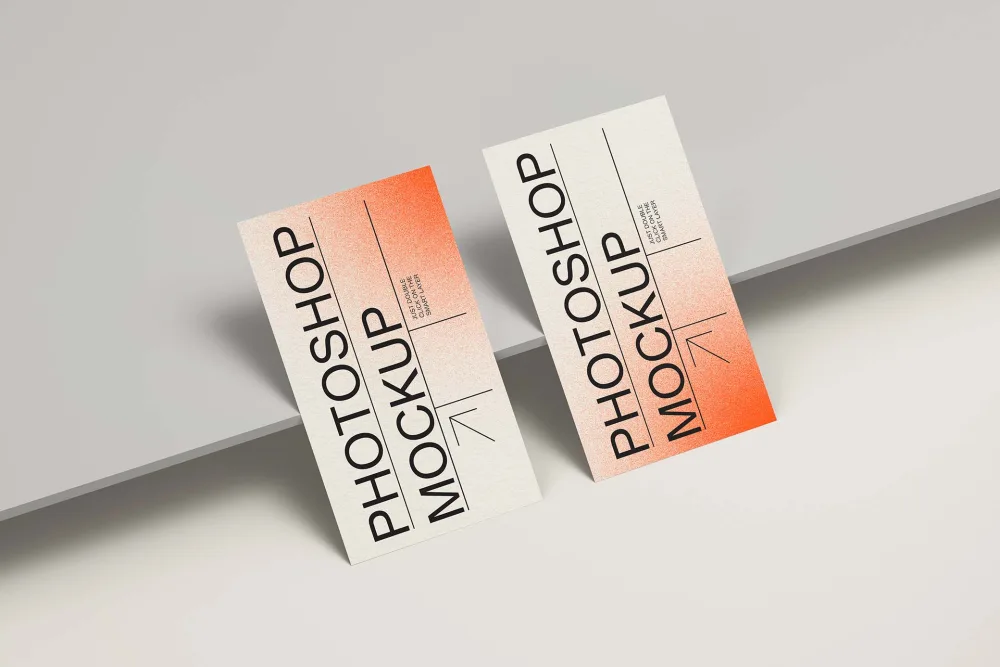 Two vertical business card mockups with a modern design, featuring a white base, black typography, and a gradient orange effect. Cards are propped against a sleek light gray surface.