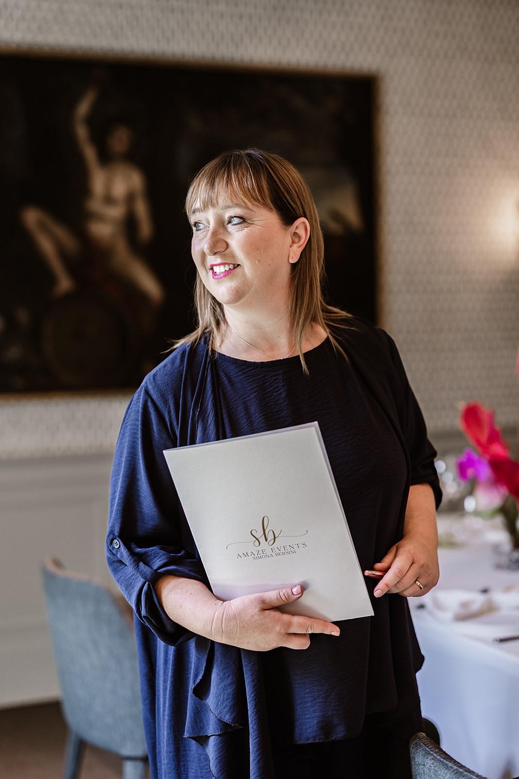 A smiling young man with crossed arms, wearing a plaid shirt and white t-shirt, poses against a dark background.