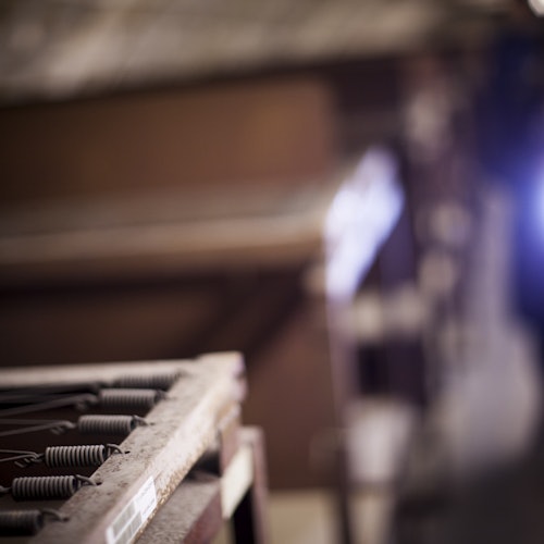 Close-up of a metal frame with springs in a dimly lit, blurred industrial setting.