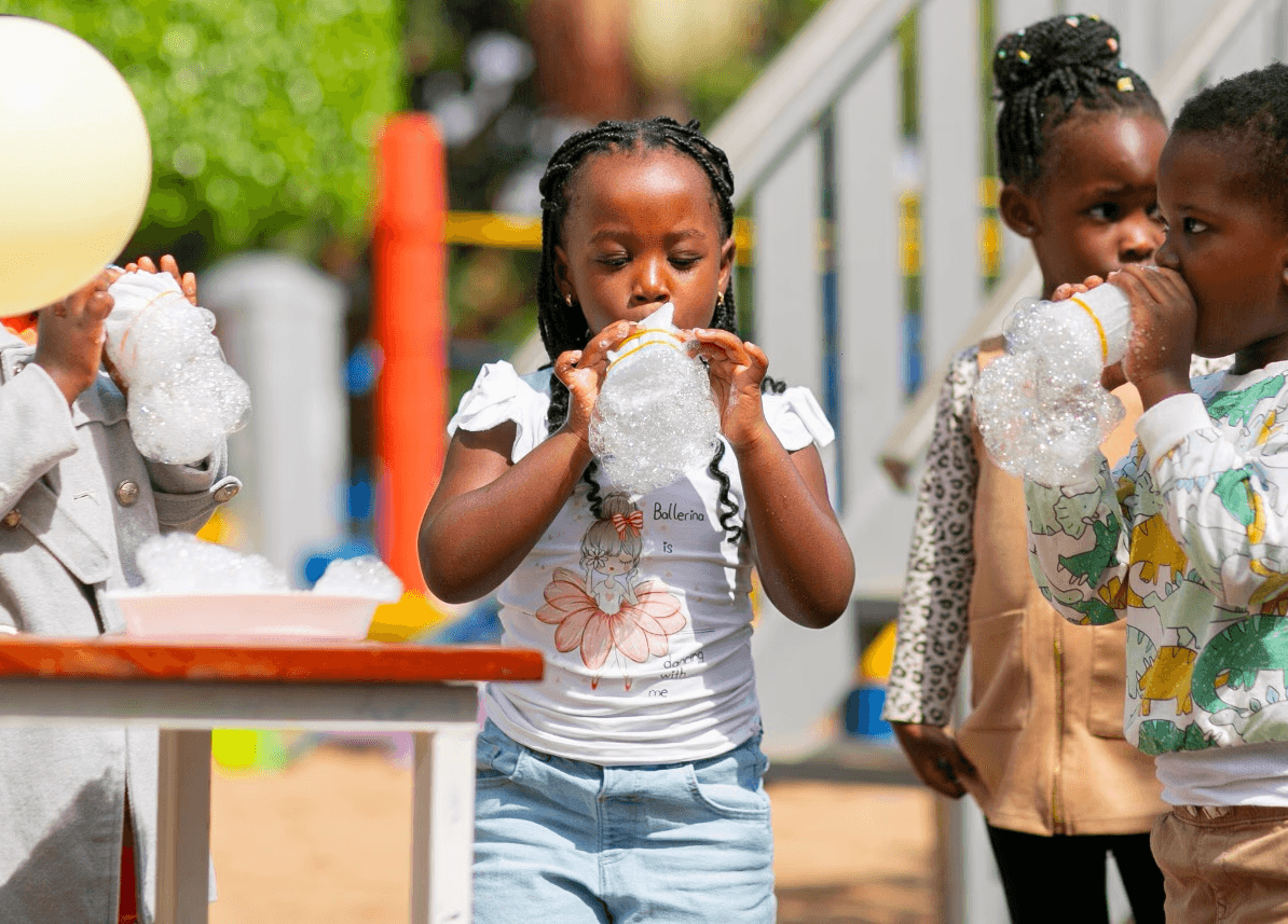 A student wearing a red uniform sits while holding a book in his hands