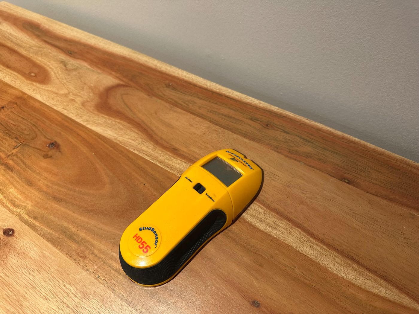 Détecteur de montants Zircon StudSensor HD55 jaune et noir posé sur une table en bois