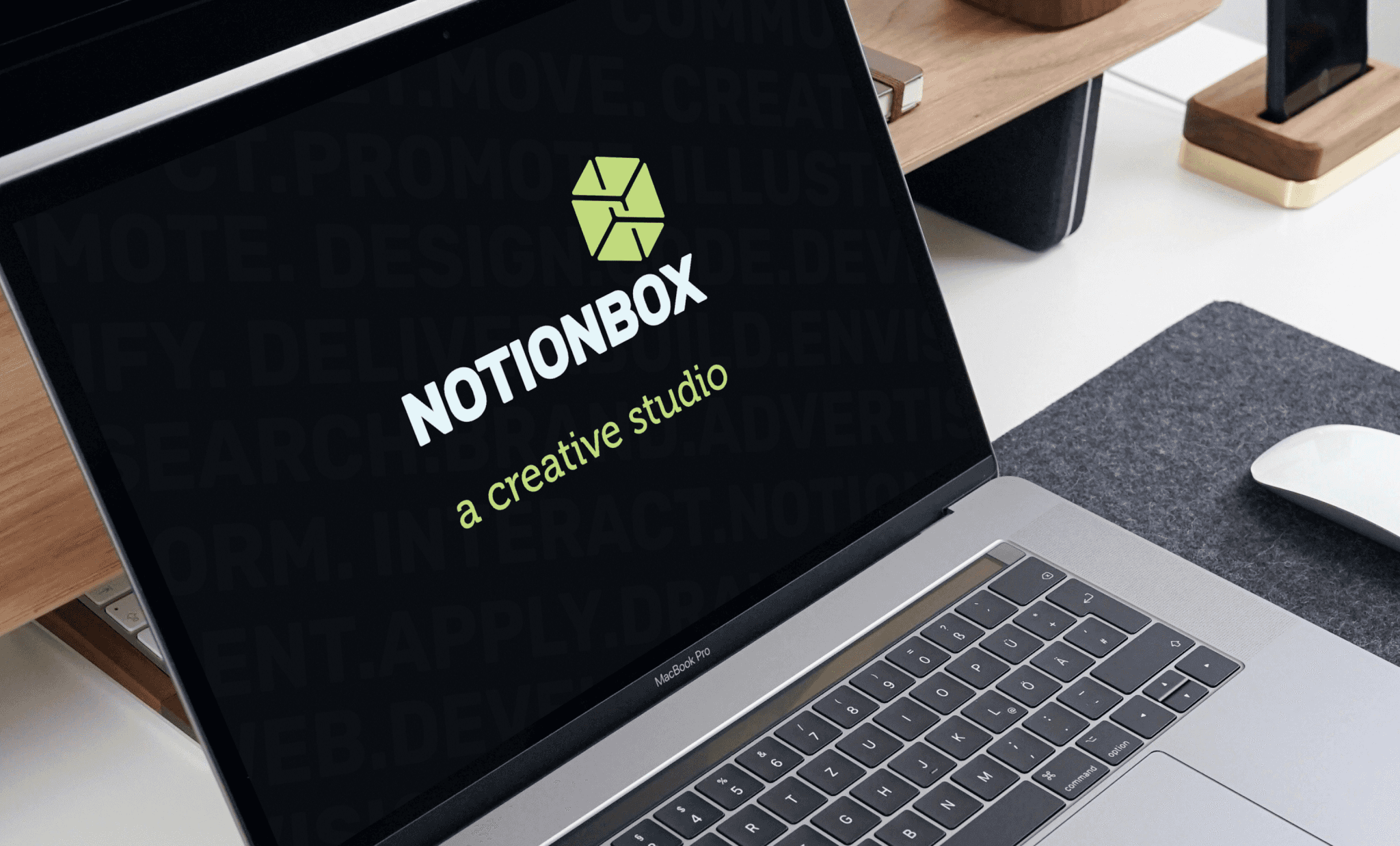 A silver laptop on a desk showing the NotionBox logo on the black screen