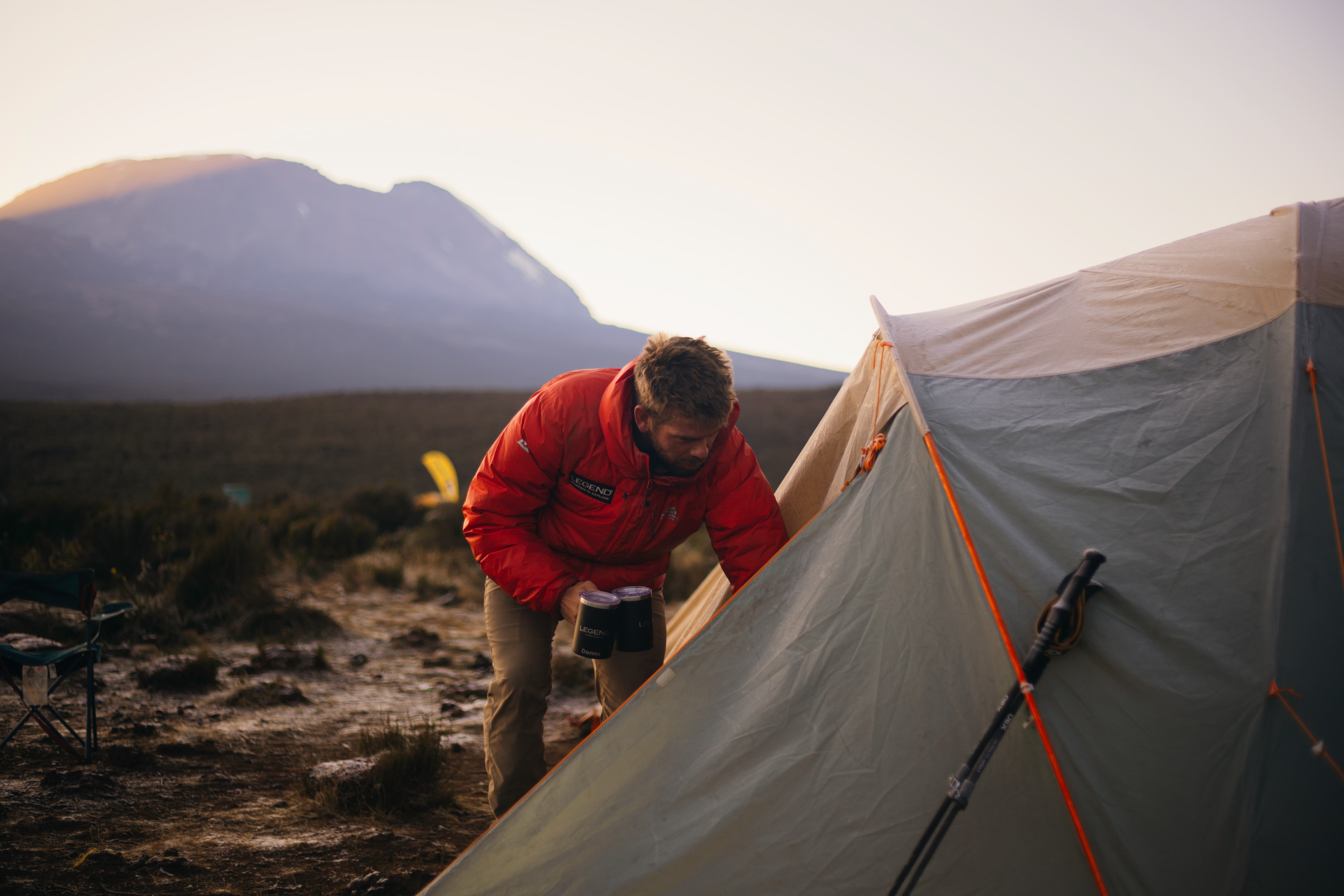 A Legend Expeditions guide checking in with a climber at camp on Kilimanjaro to assess altitude sickness symptoms.