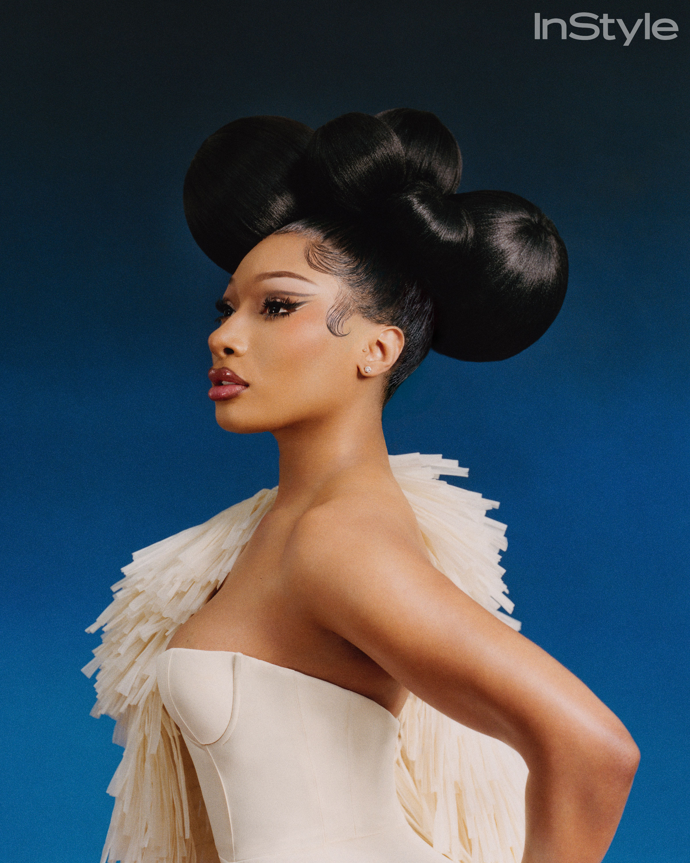 Profile portrait of Megan Thee Stallion against a deep blue backdrop