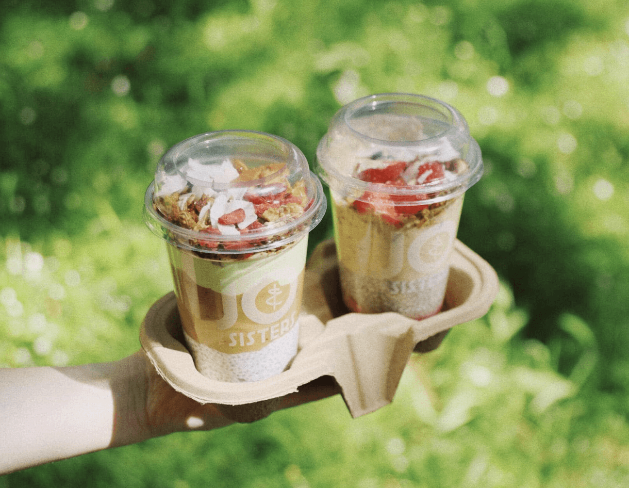 Chia pudding cups with granola and fruit from Jo & The Sisters Morning Club served outdoors on a sunny day