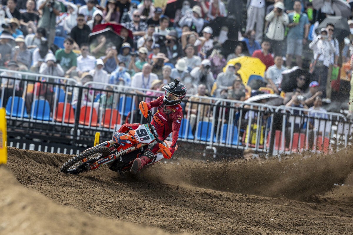 Jeremy Seewer of the Van Venrooy KTM Racing Team powers through a sandy corner during the MXGP of China, kicking up roost as spectators watch from the trackside stands.